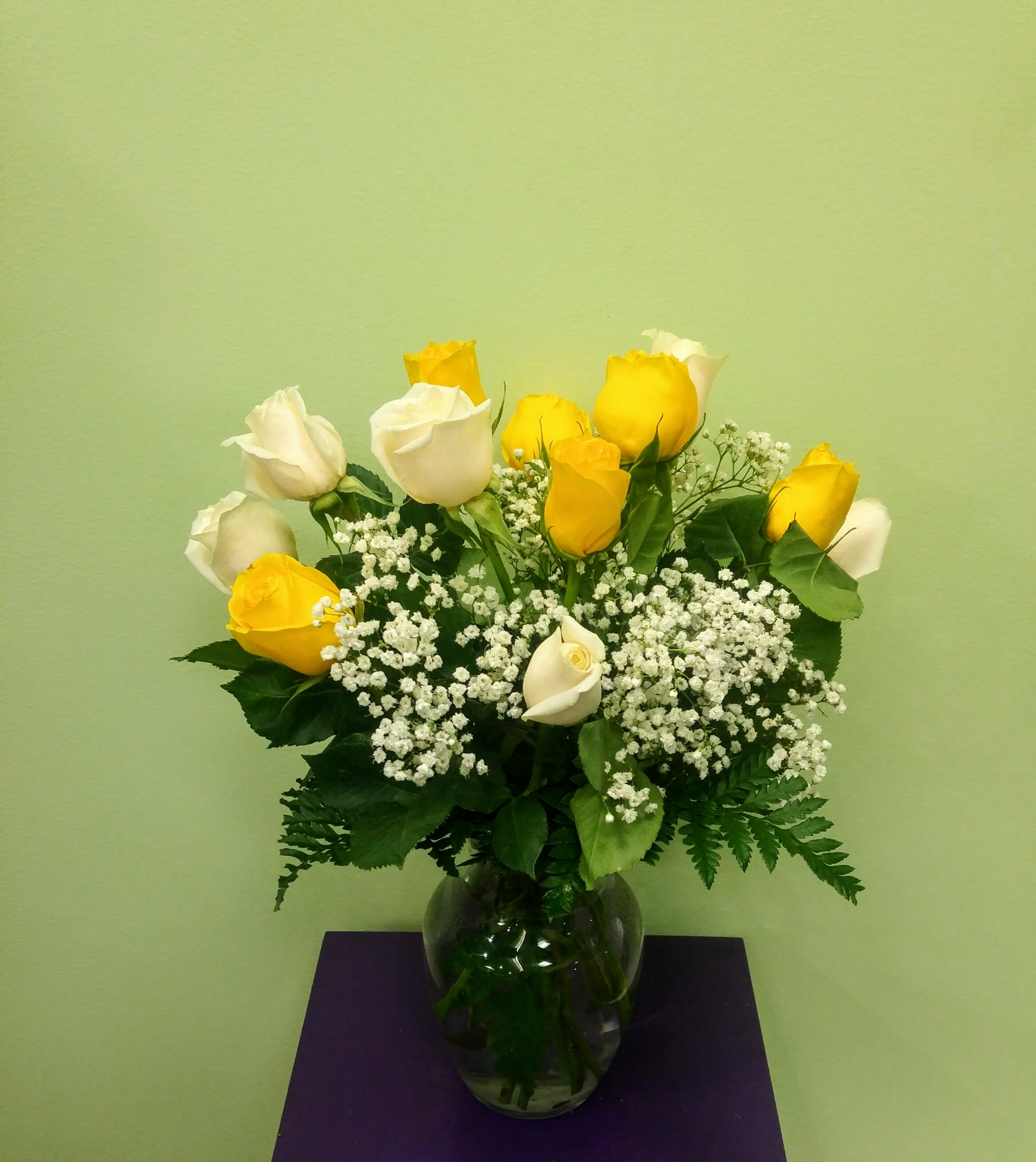 Yellow and white roses in a glass vase with baby's breath
