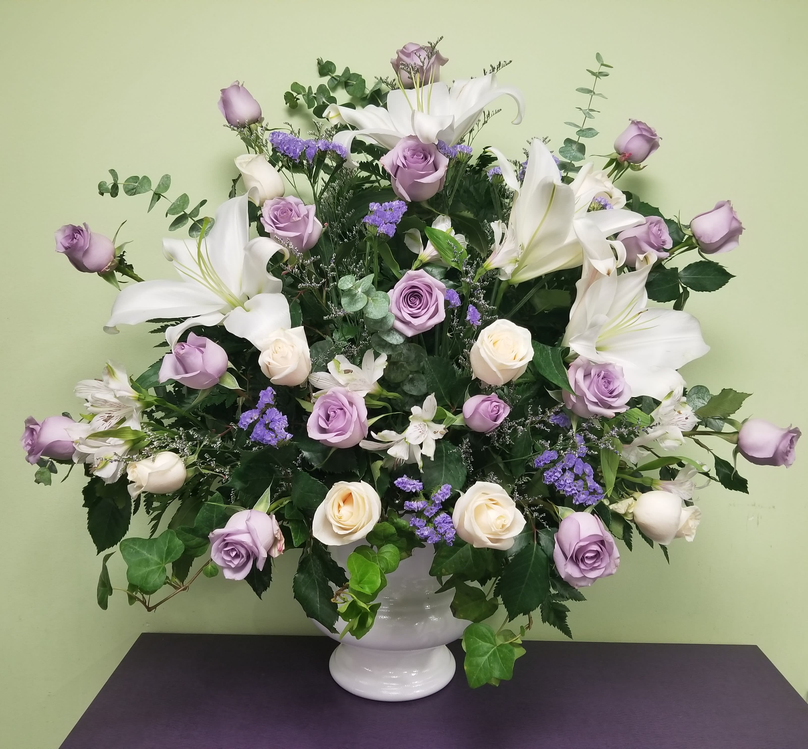 Lavender roses and white lilies arranged in a white vase