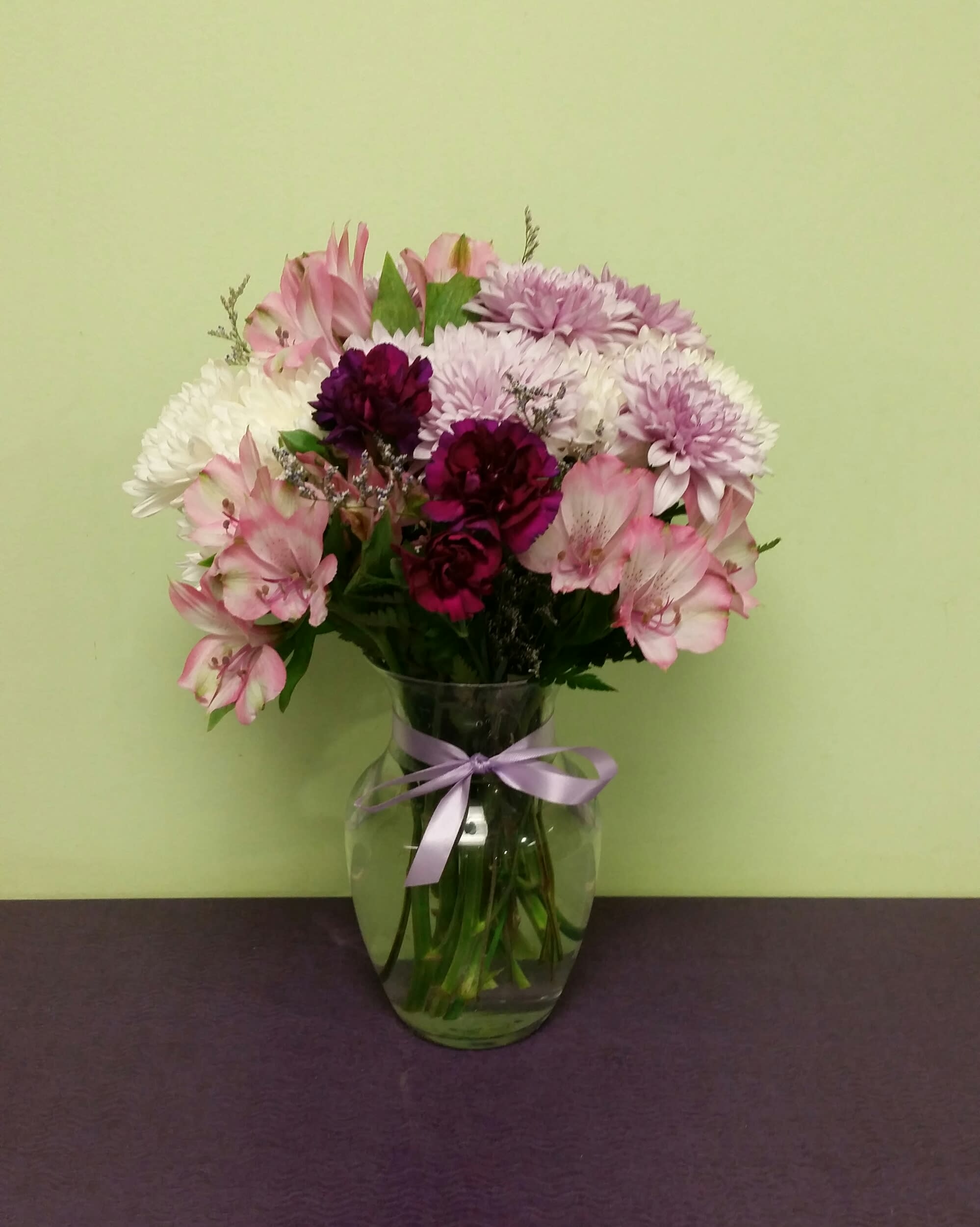 Pink and white mixed bouquet in a glass vase with a lavender ribbon