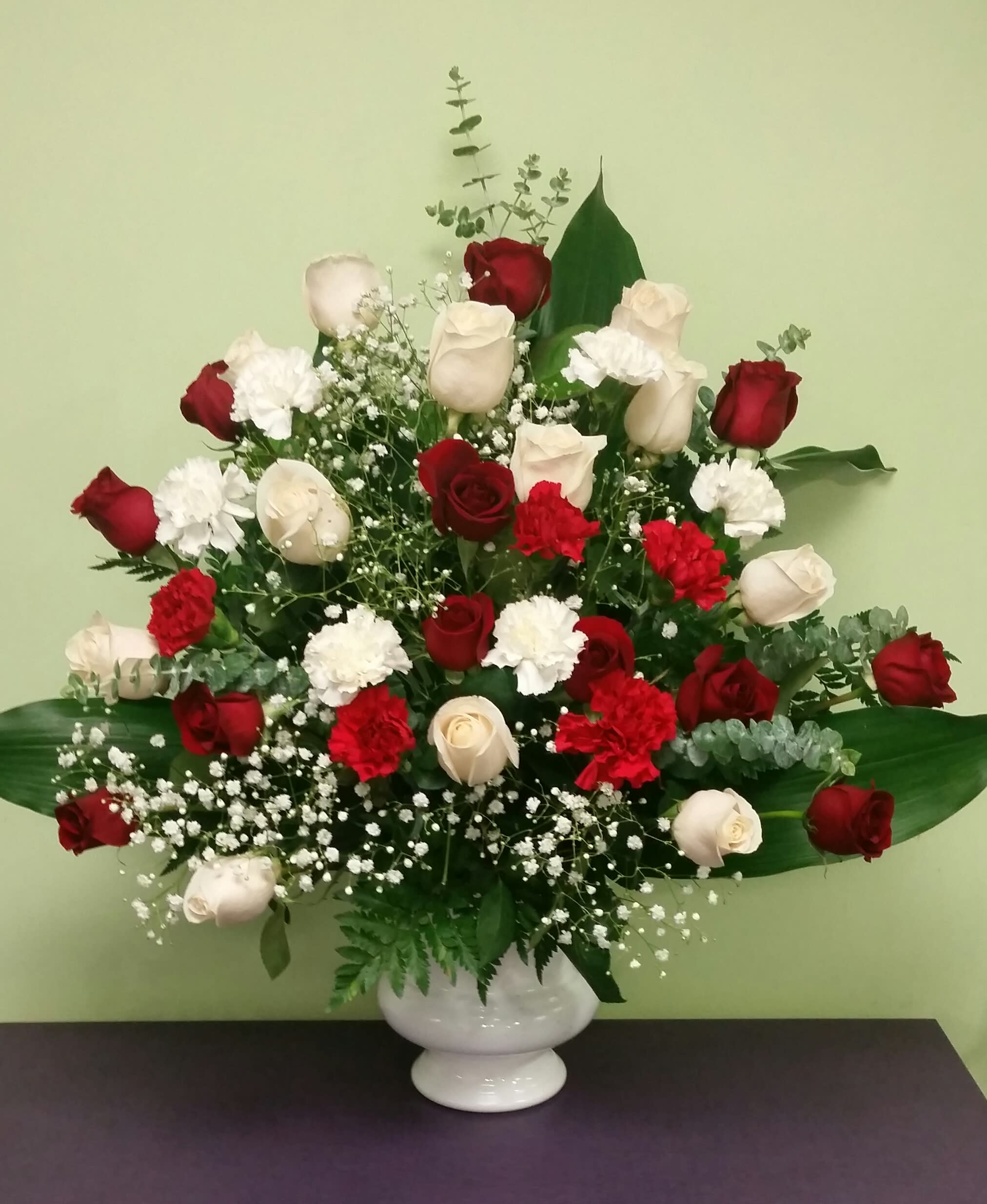 Red and white roses with carnations in a white vase