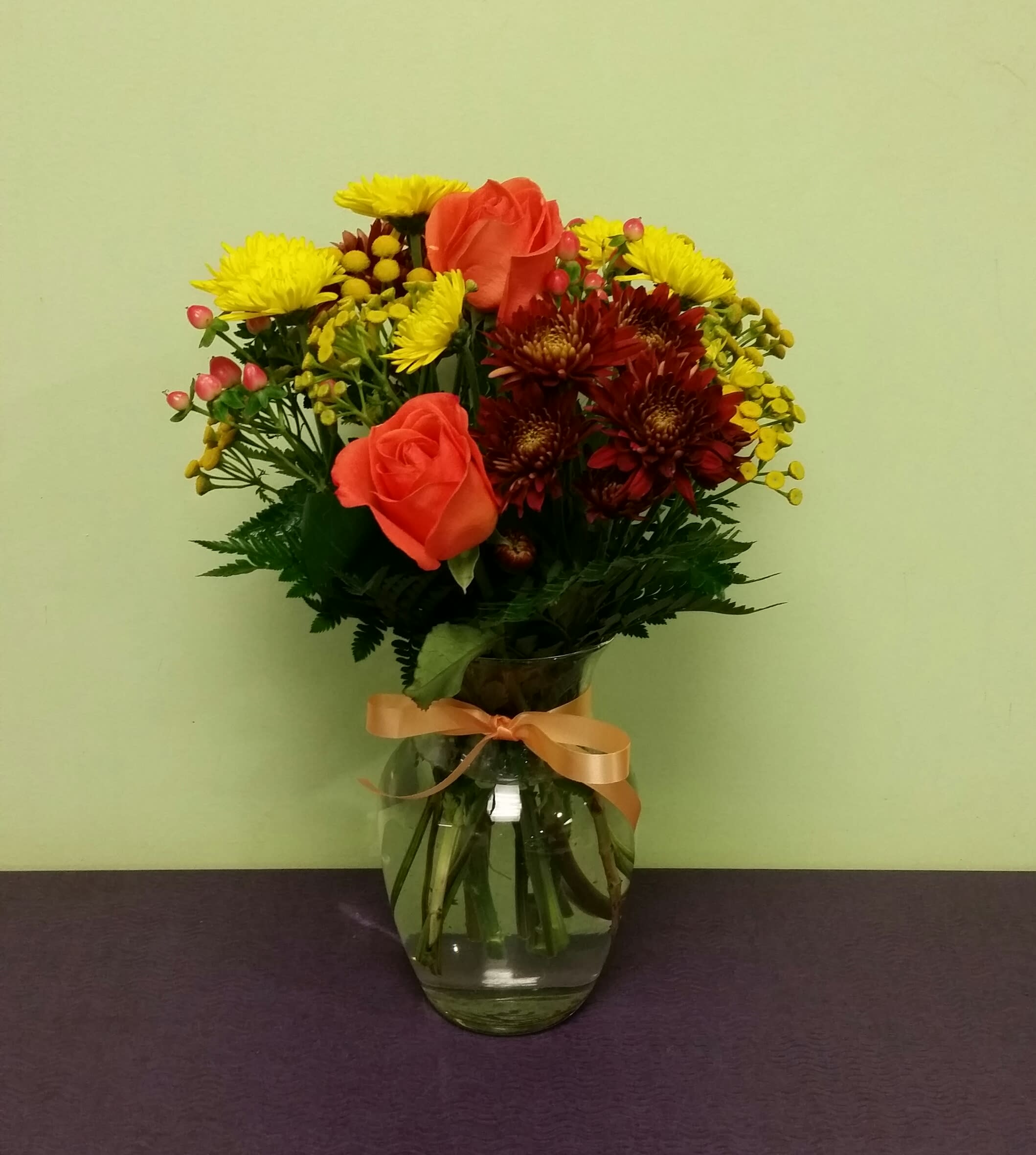 Bouquet of orange roses and yellow chrysanthemums in a glass vase