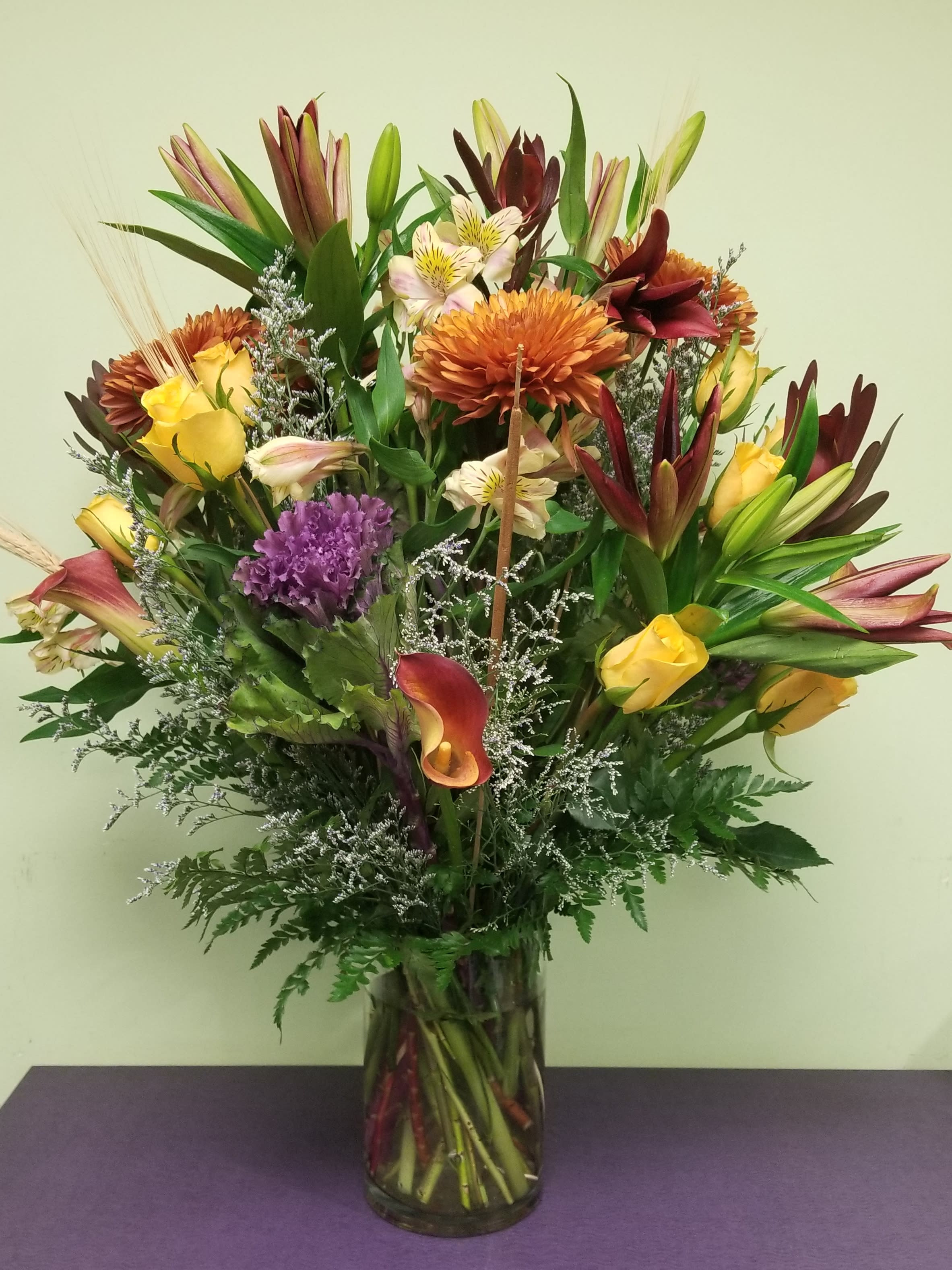 Mixed bouquet of lilies, roses, calla lilies, and chrysanthemums in a glass vase