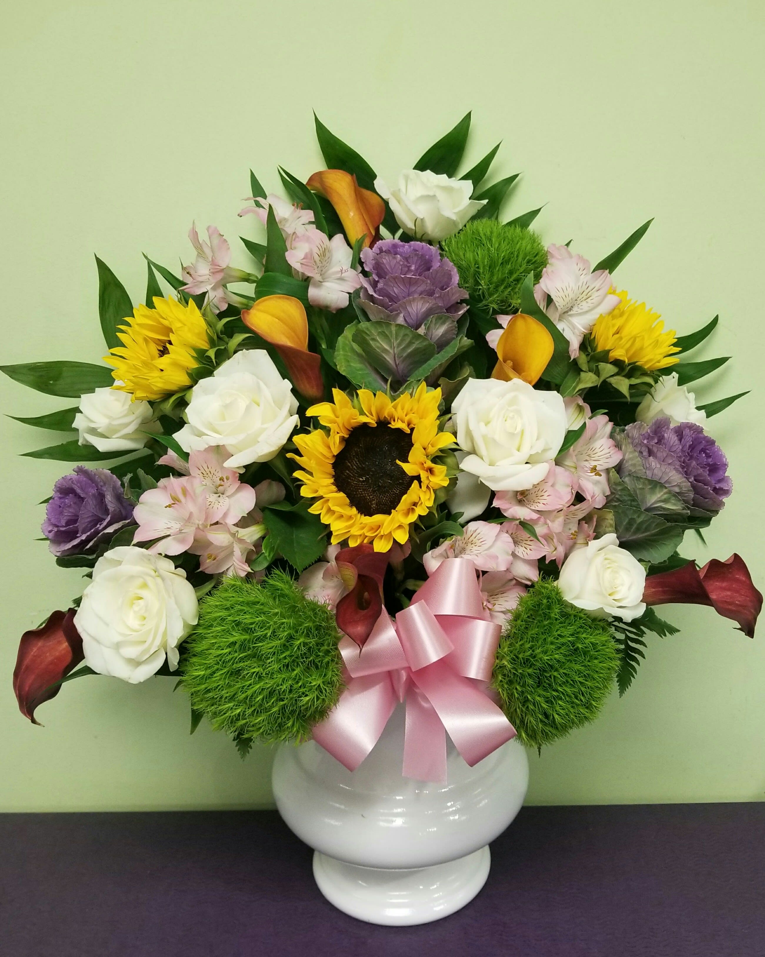 Mixed bouquet in a white vase with roses, sunflowers, and calla lilies