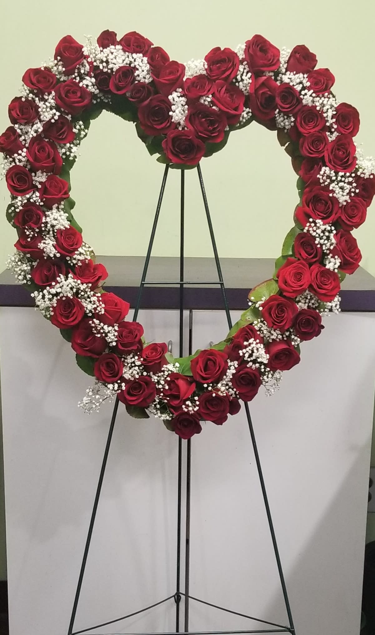Heart-shaped rose wreath on a black stand