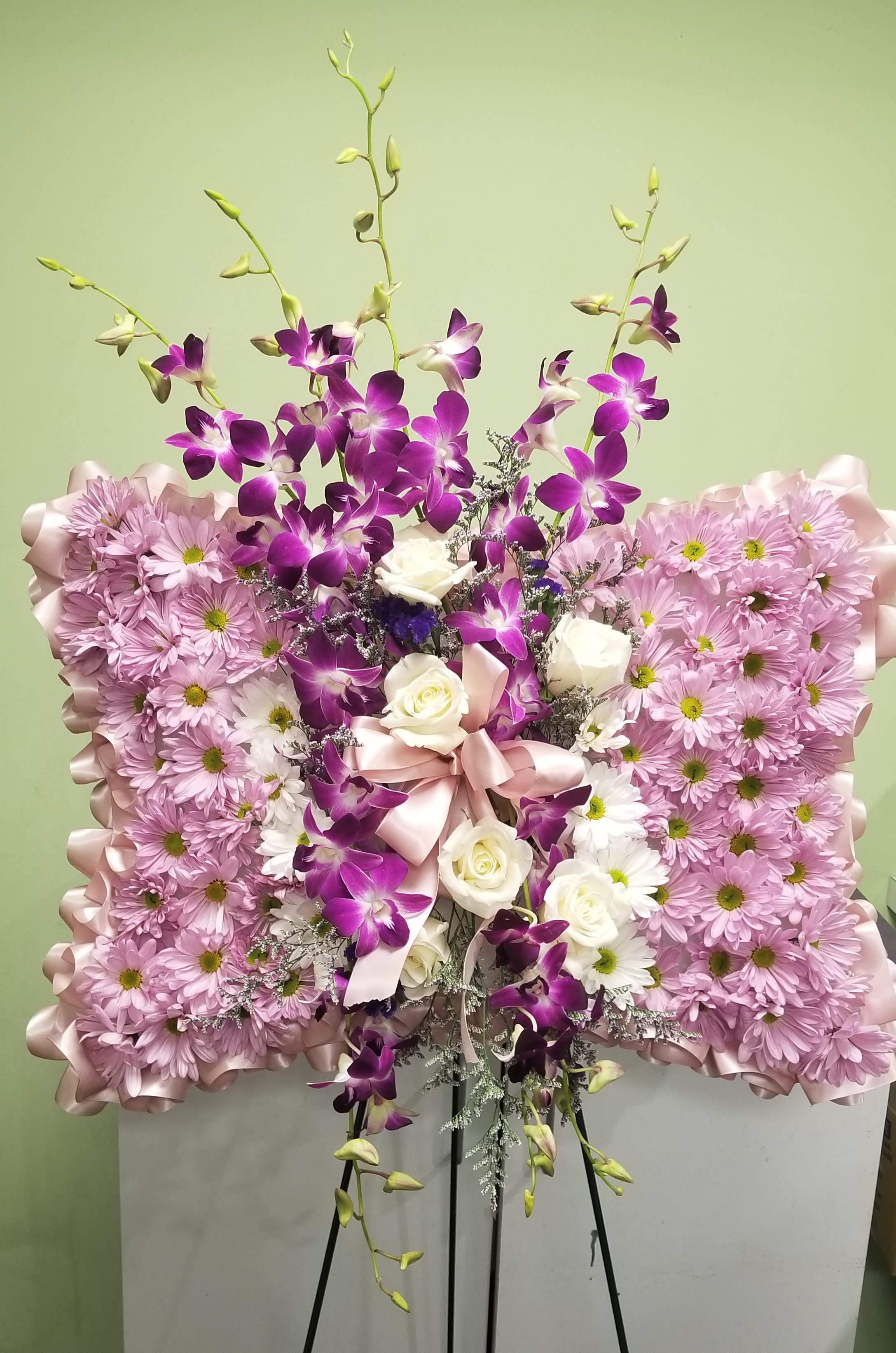 Pink and purple floral standing arrangement with white roses on an easel