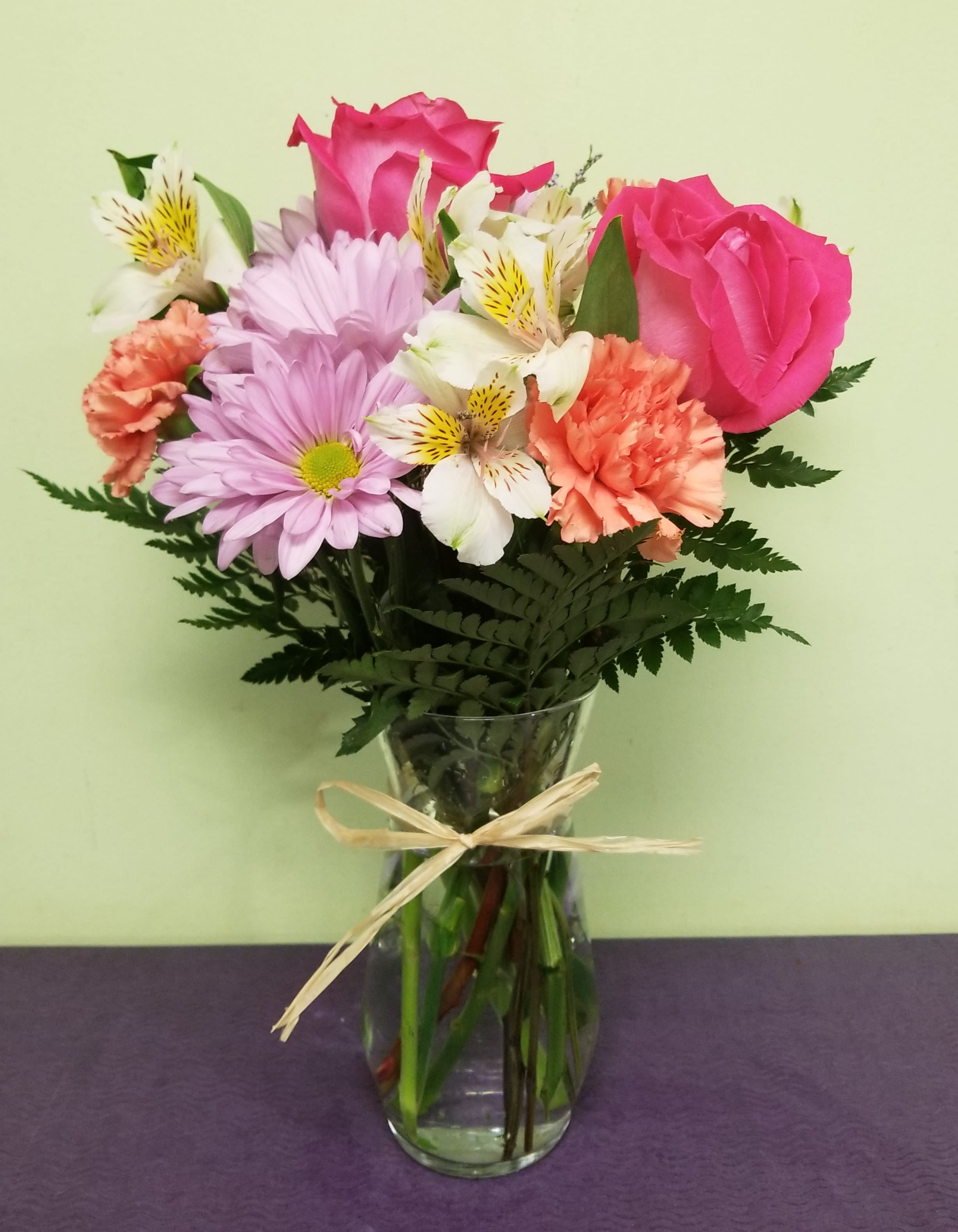 Bouquet of pink roses, lavender daisies, and white alstroemeria in a glass vase