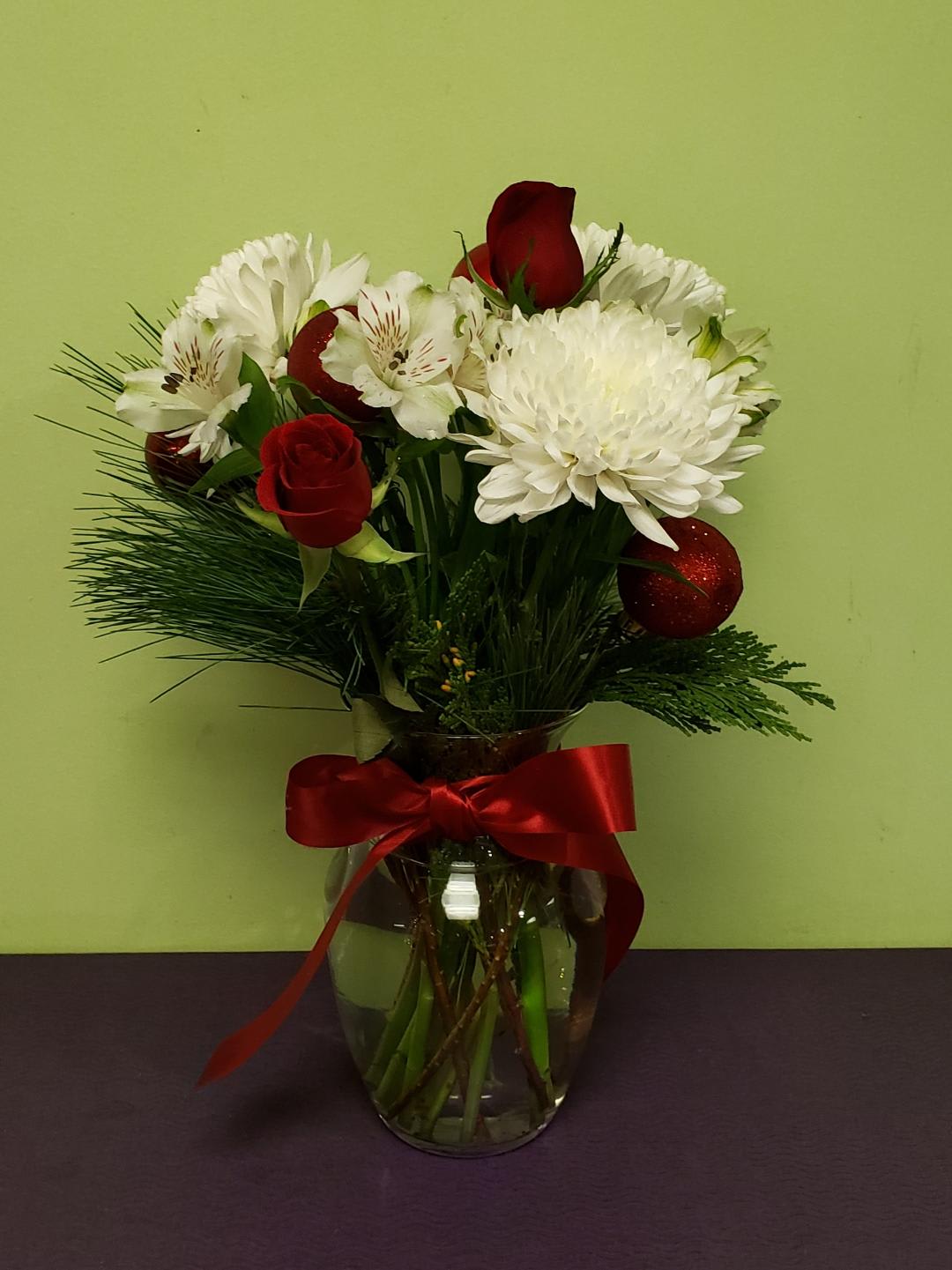 Bouquet of red roses and white flowers in a glass vase with a red ribbon
