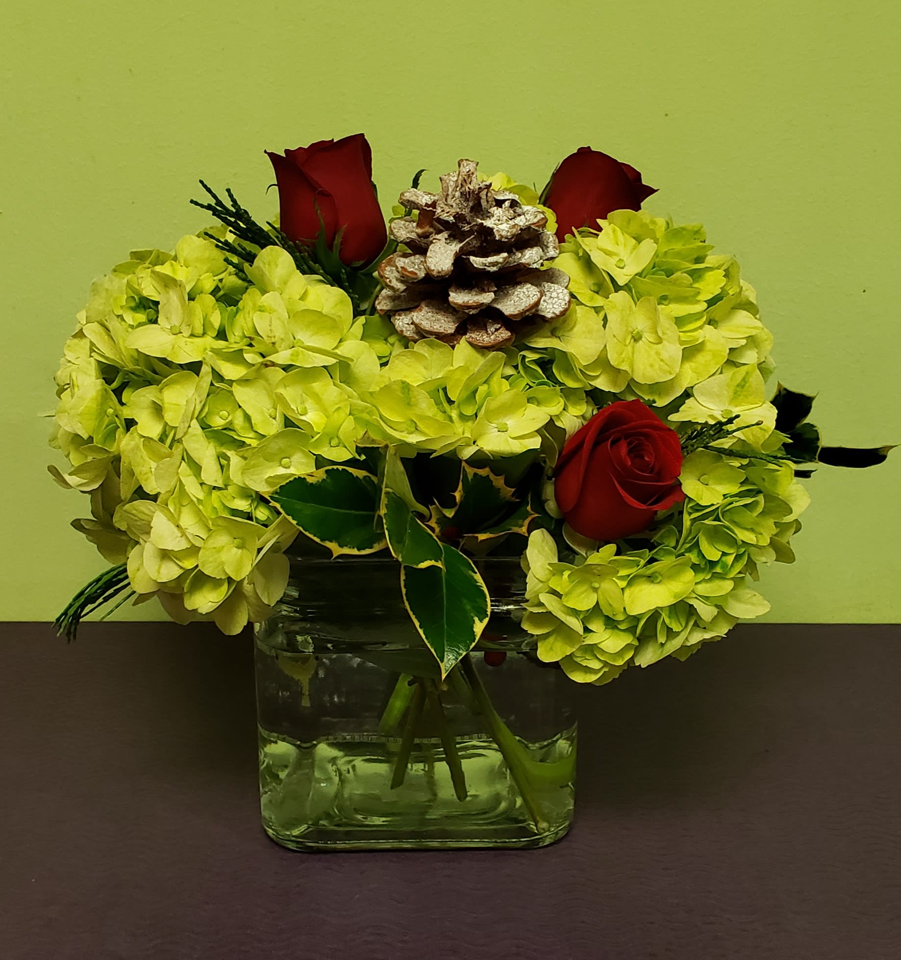 Yellow hydrangea arrangement with red roses in a glass vase