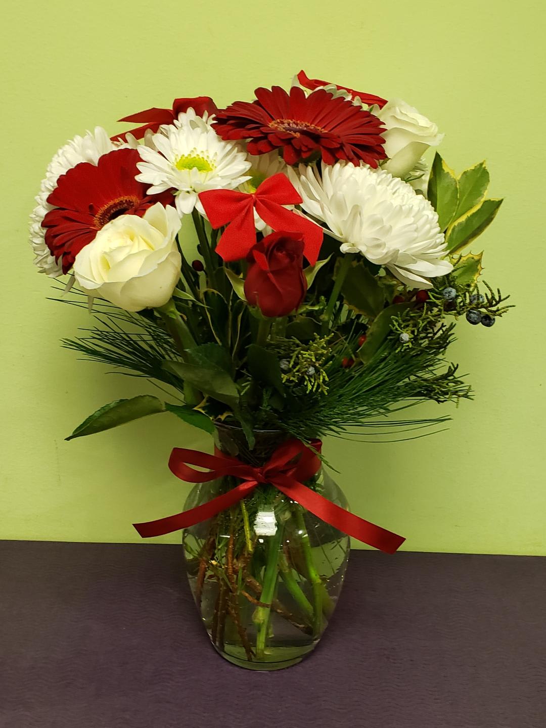 Bouquet of red and white flowers in a glass vase with a red ribbon