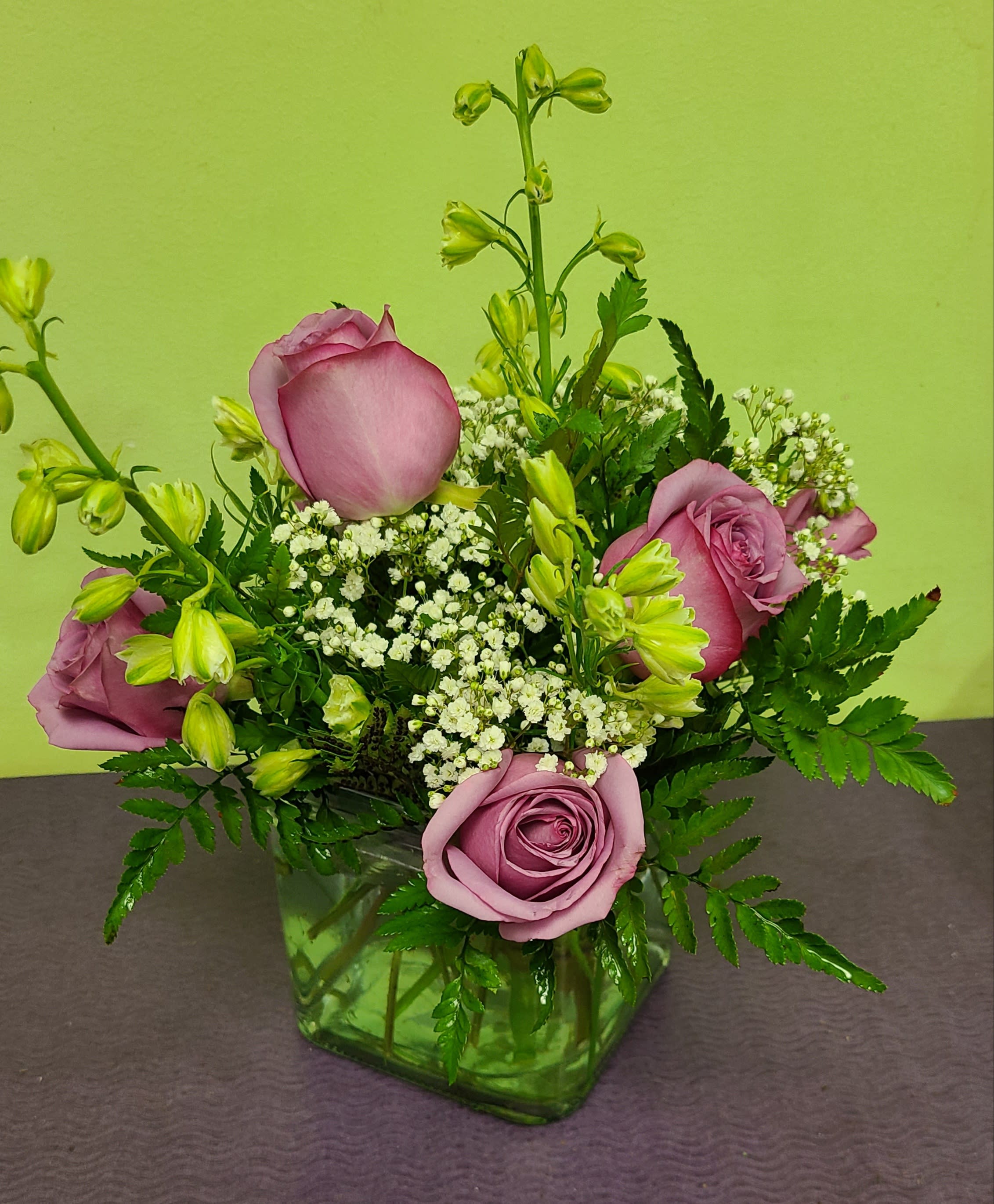 Pink roses and white filler flowers in a green glass vase