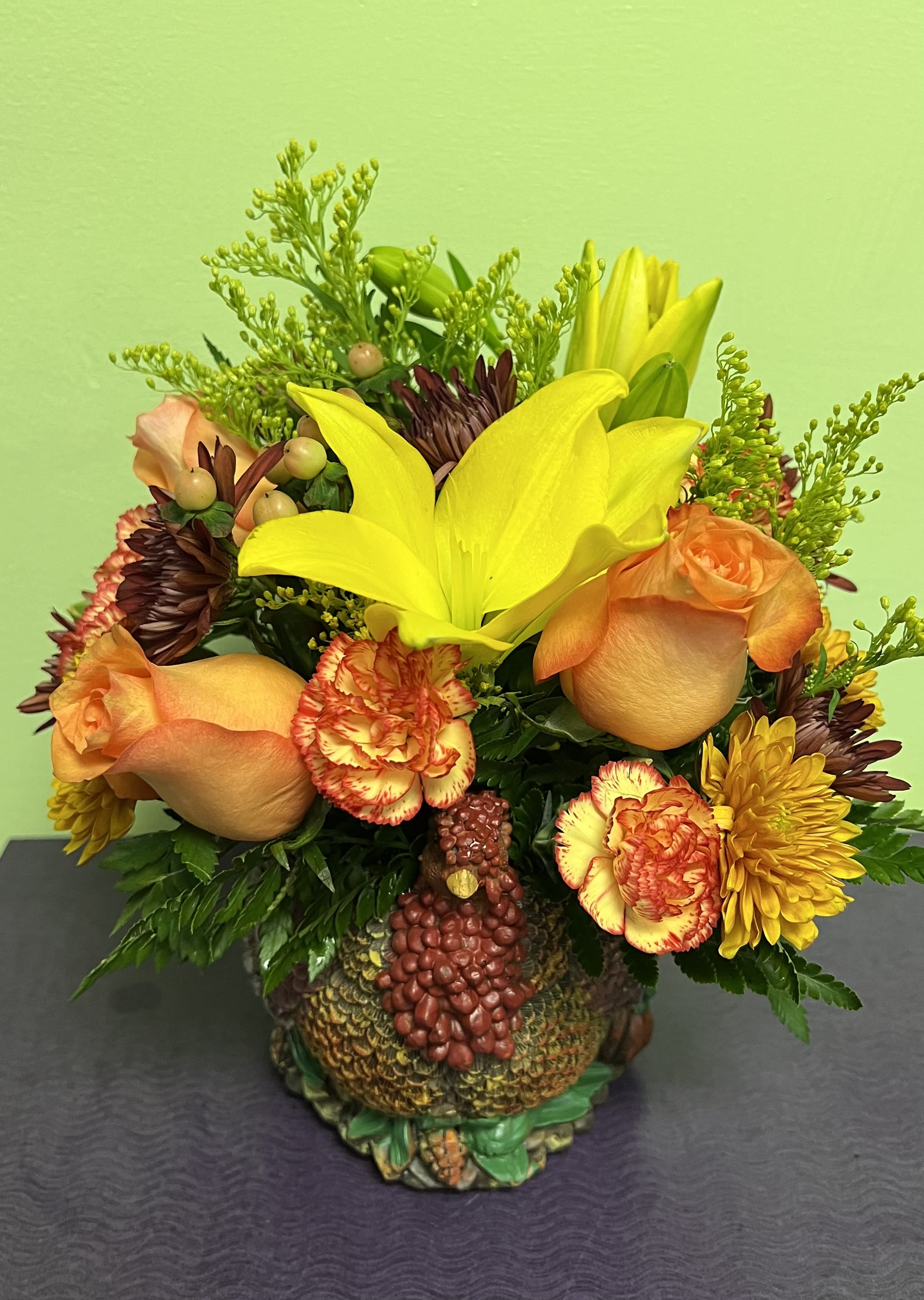 Bouquet of yellow lilies, orange roses, and carnations in a turkey-shaped container