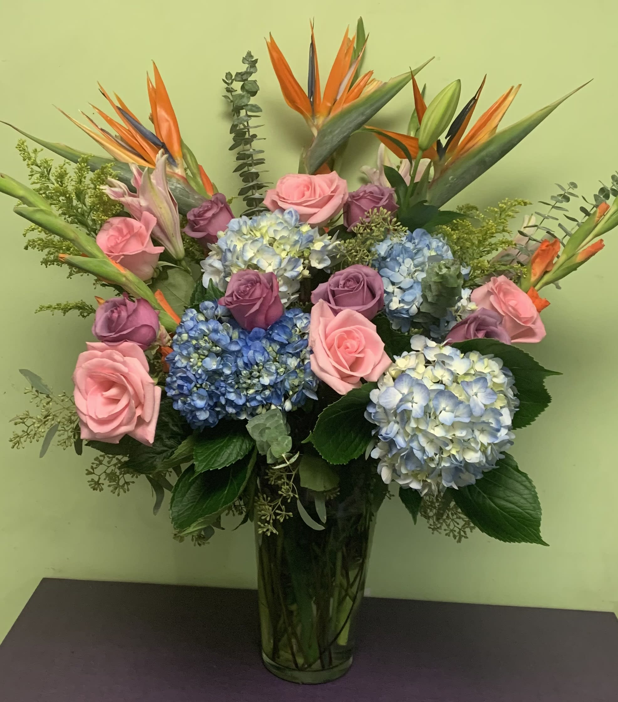 Bouquet of pink and purple roses with blue hydrangeas in a glass vase
