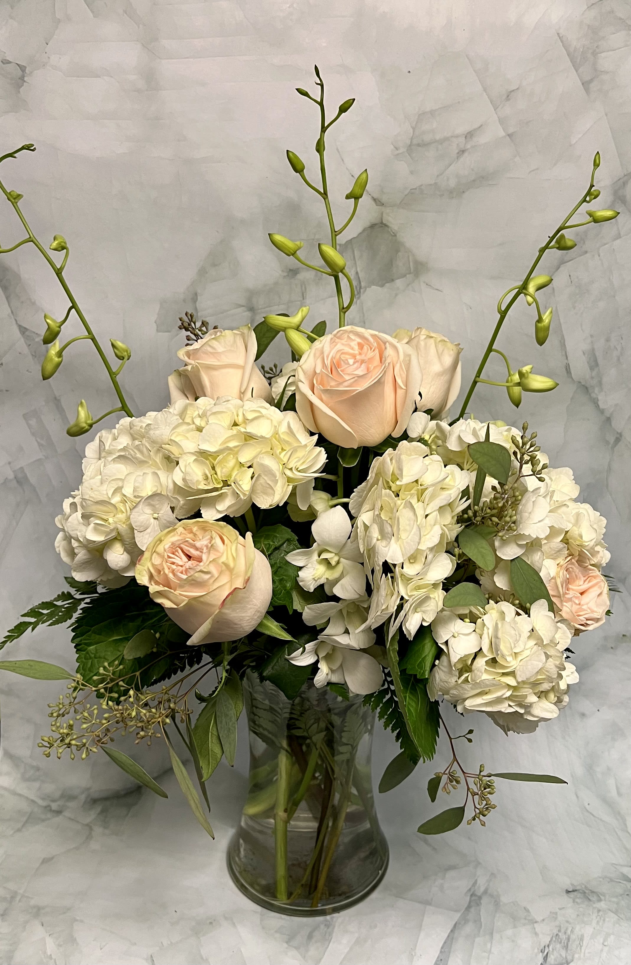 Cream and blush roses with white hydrangeas in a glass vase
