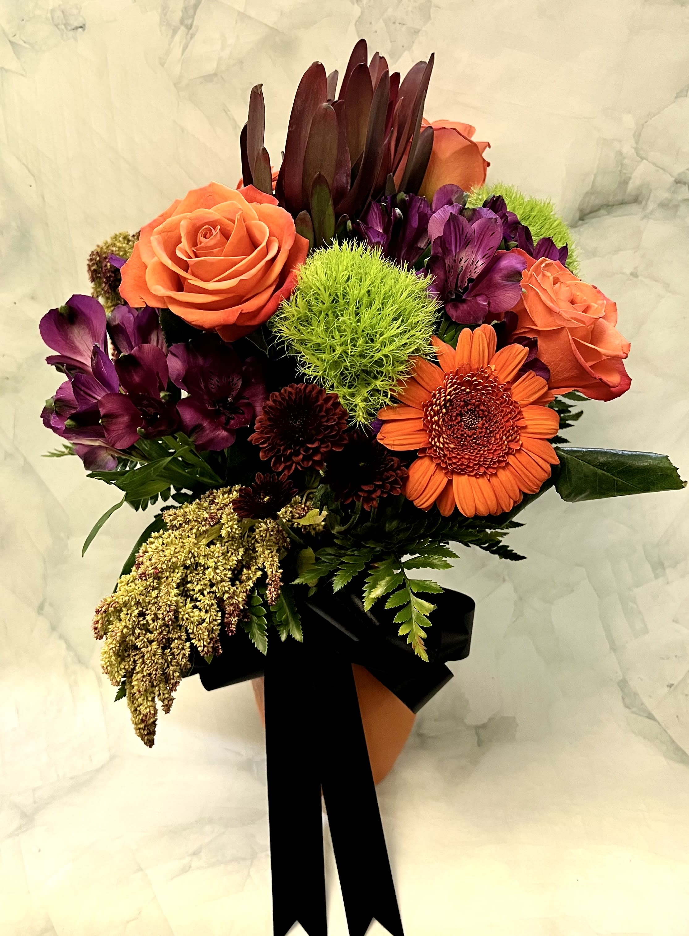 Bouquet of orange roses and purple flowers with a black ribbon