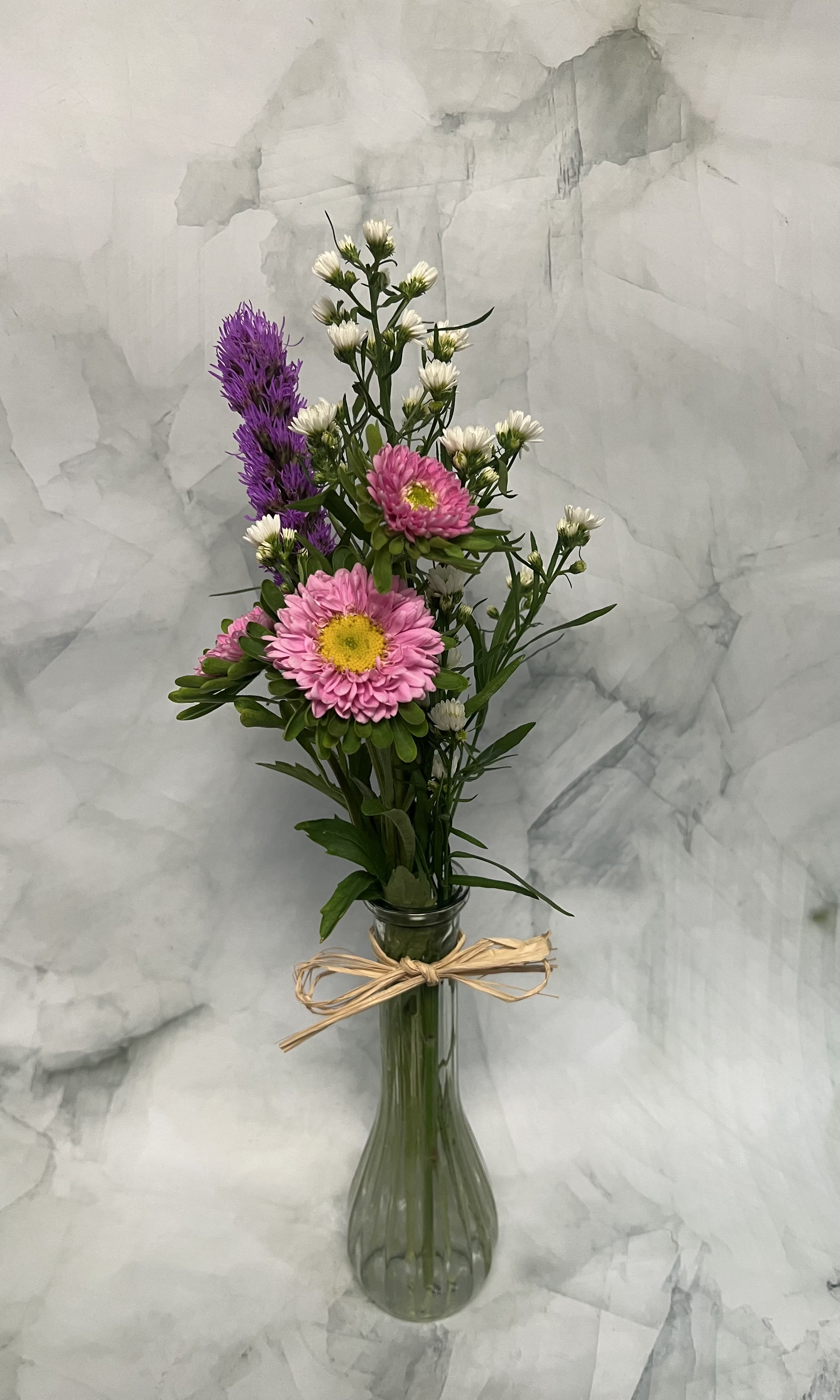 Pink and white flowers in a tall glass vase tied with raffia