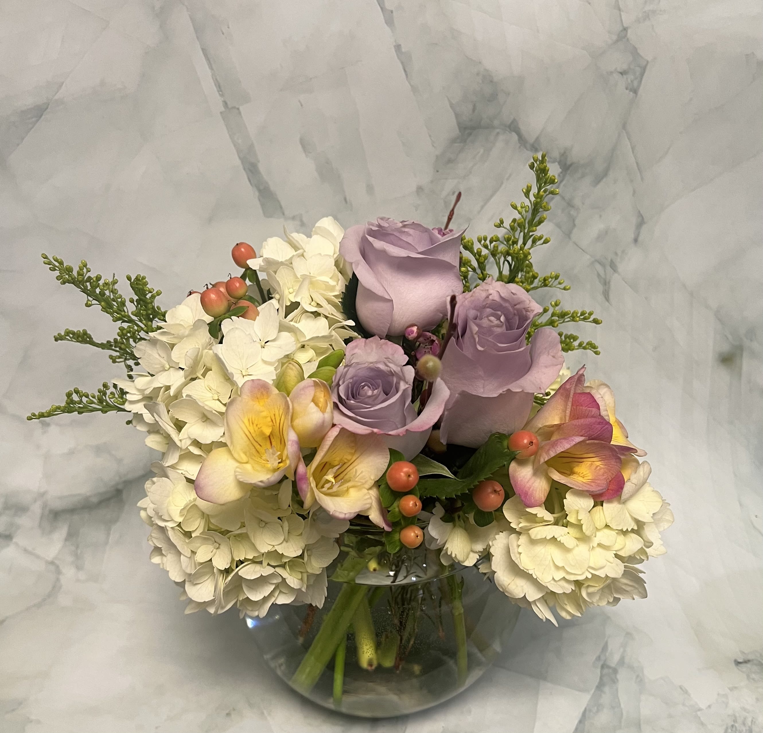 Lavender roses and white hydrangeas in a clear glass vase