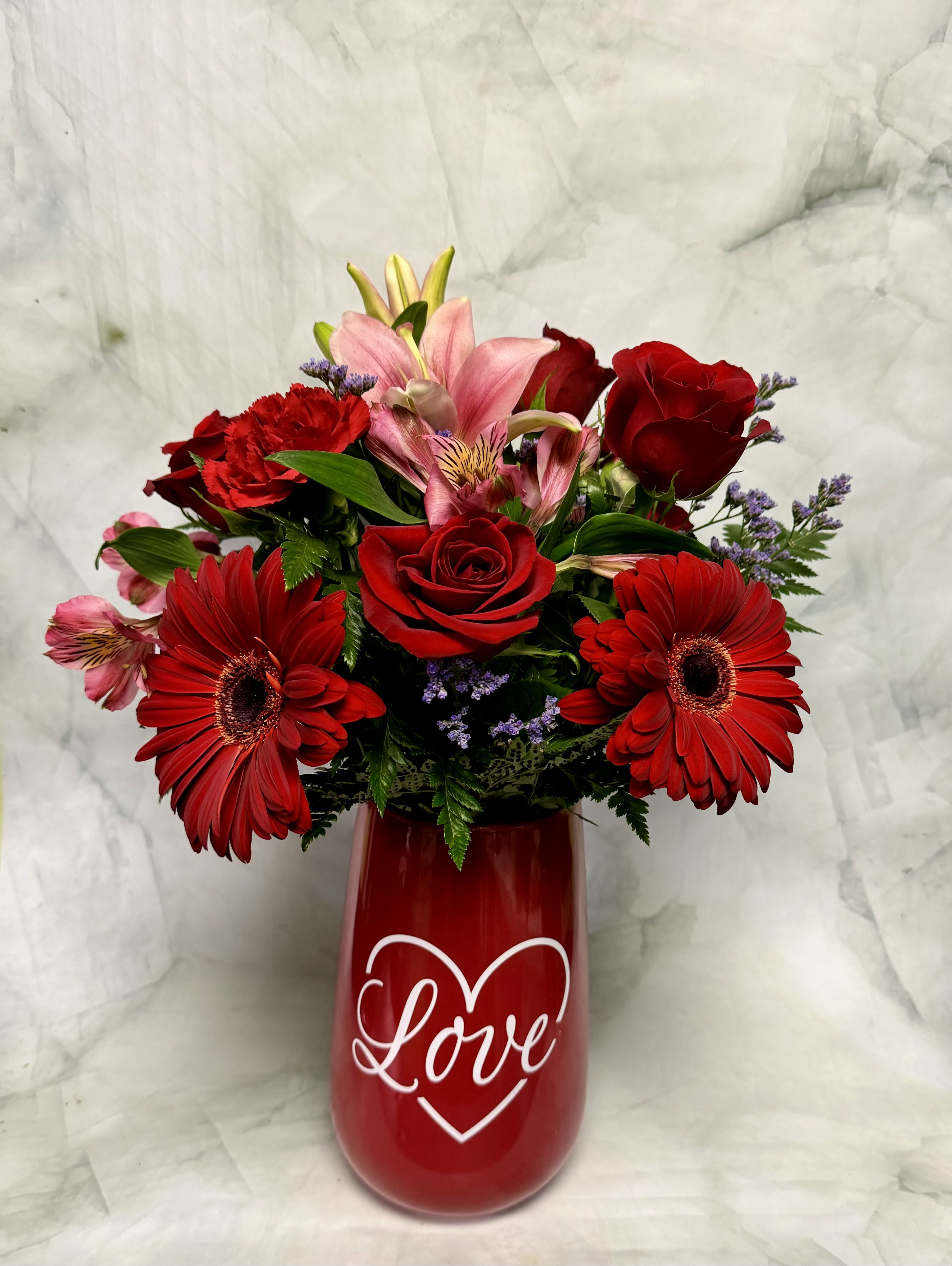 Red and pink mixed bouquet in a red vase with a heart and the word Love