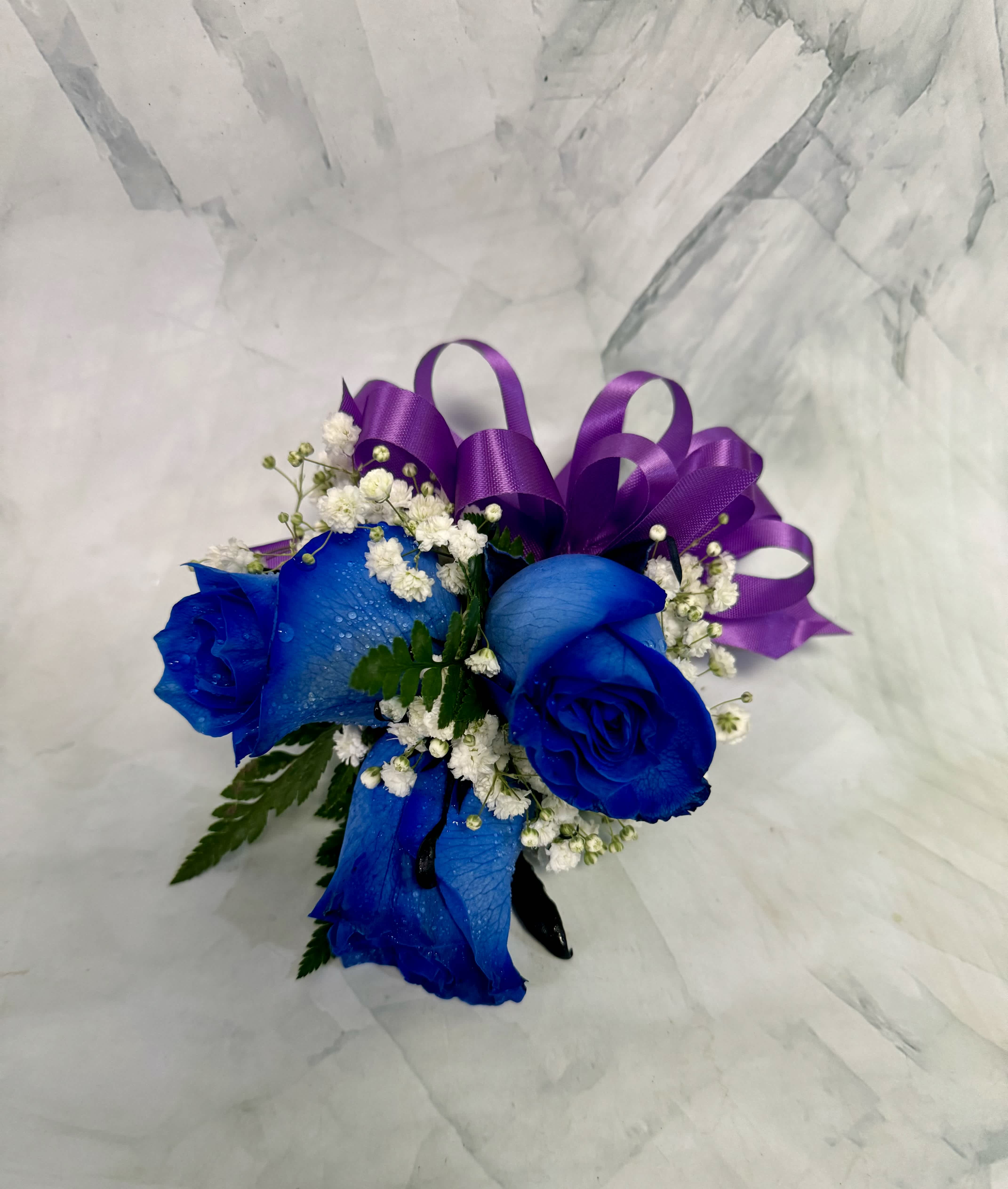 Blue roses with white baby's breath and a purple ribbon