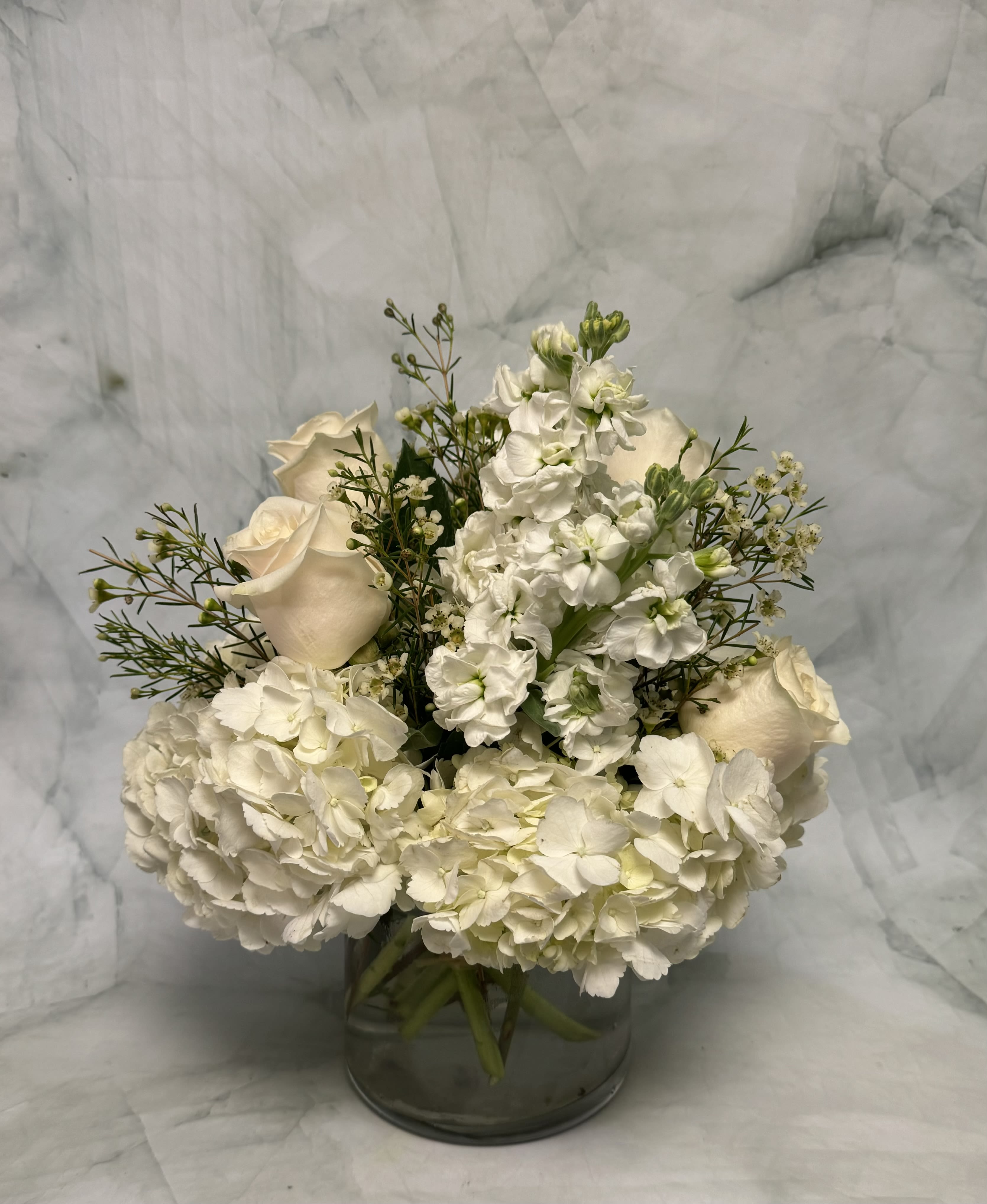 White roses and hydrangeas arranged in a glass vase