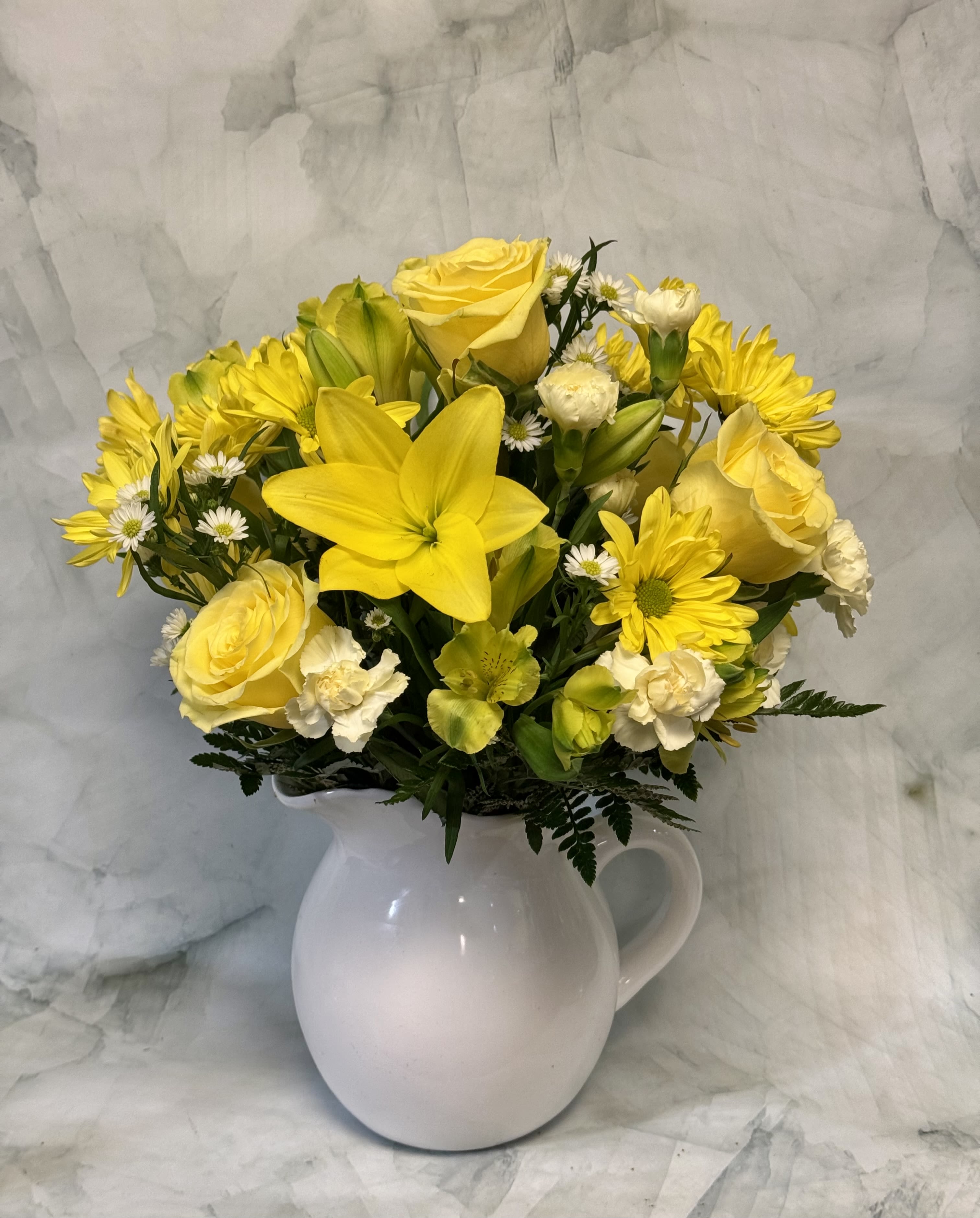 Yellow flowers arranged in a white pitcher vase