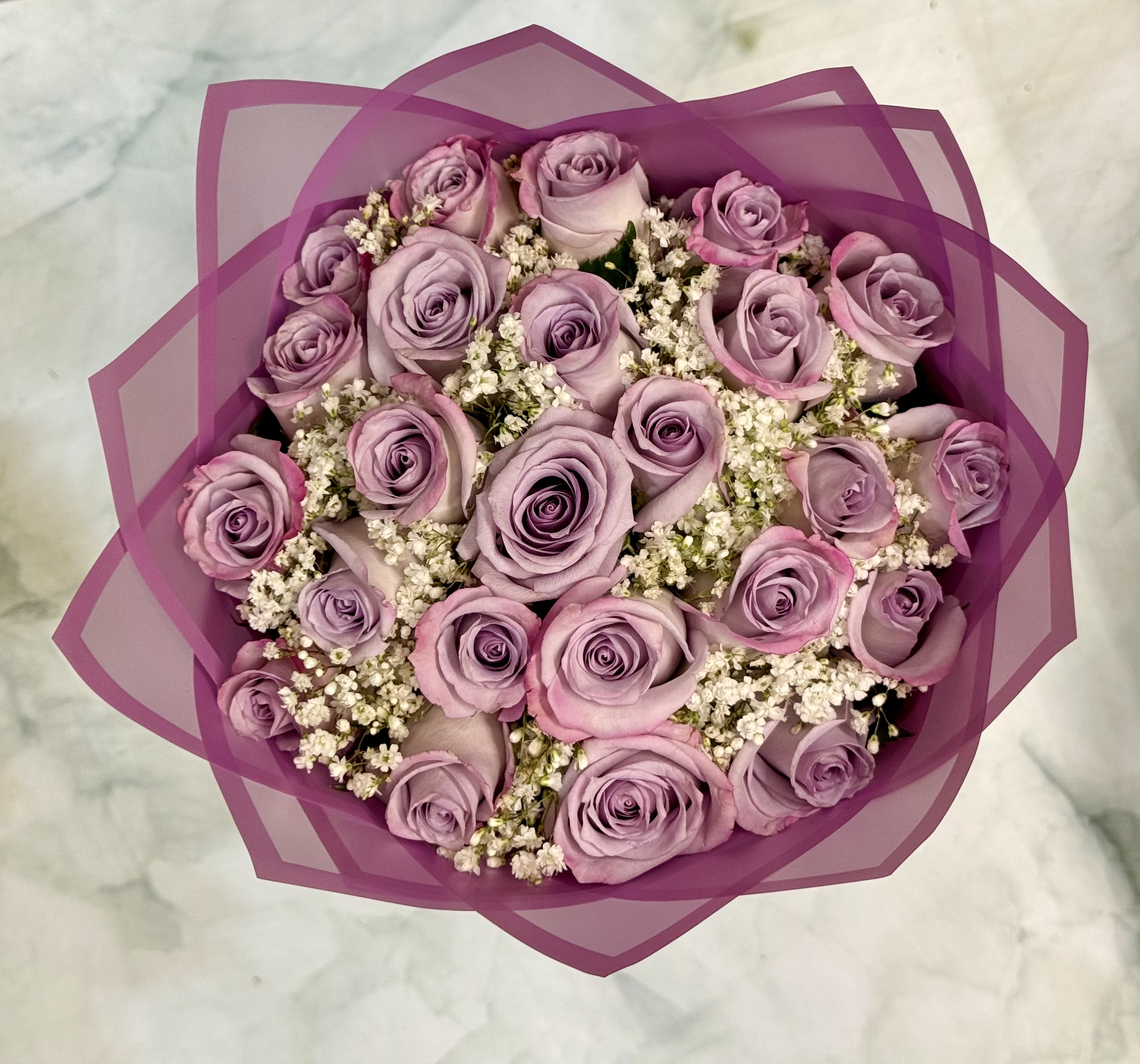 Bouquet of lavender roses with white filler flowers wrapped in purple paper