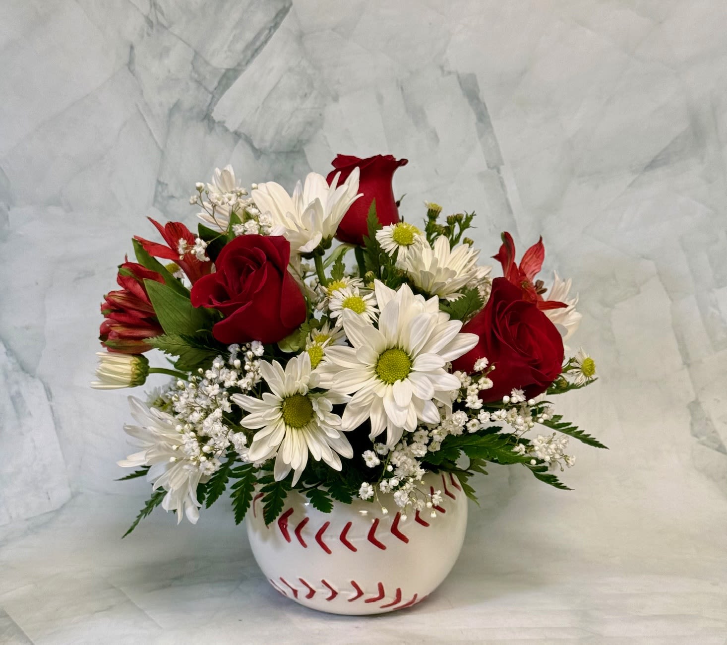 Red roses and white daisies in a baseball-shaped vase