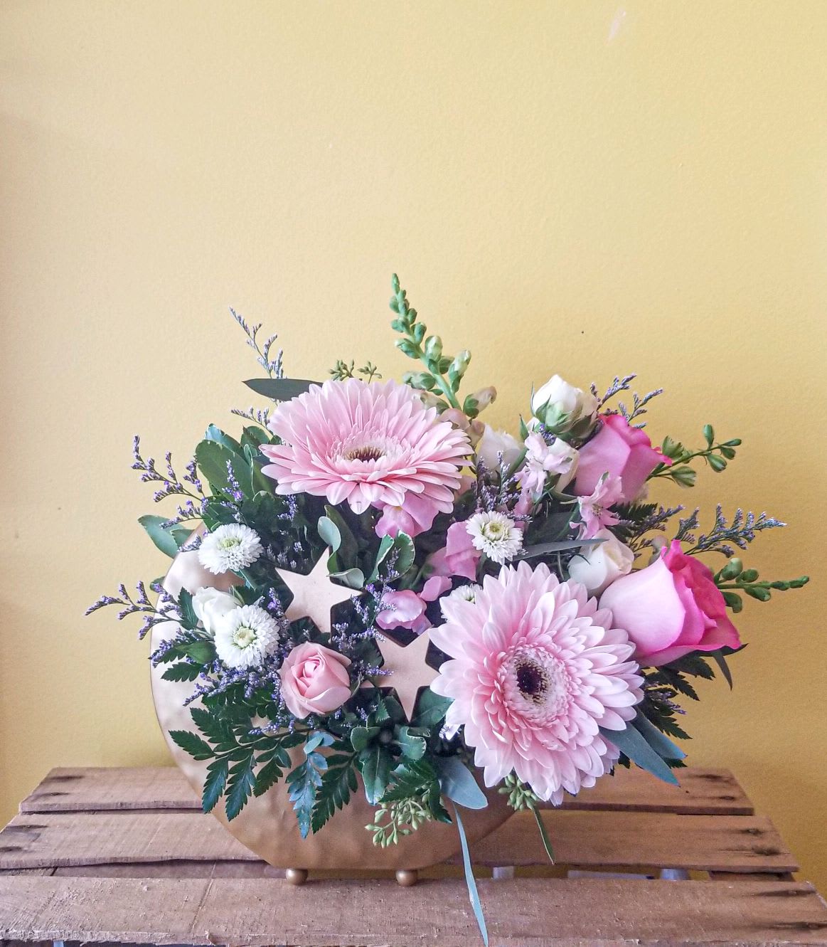 Pink gerbera daisies and roses in a low gold vase
