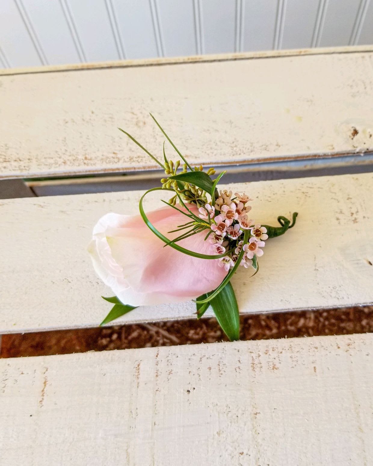 Small pink and white boutonniere with tiny blossoms and greenery