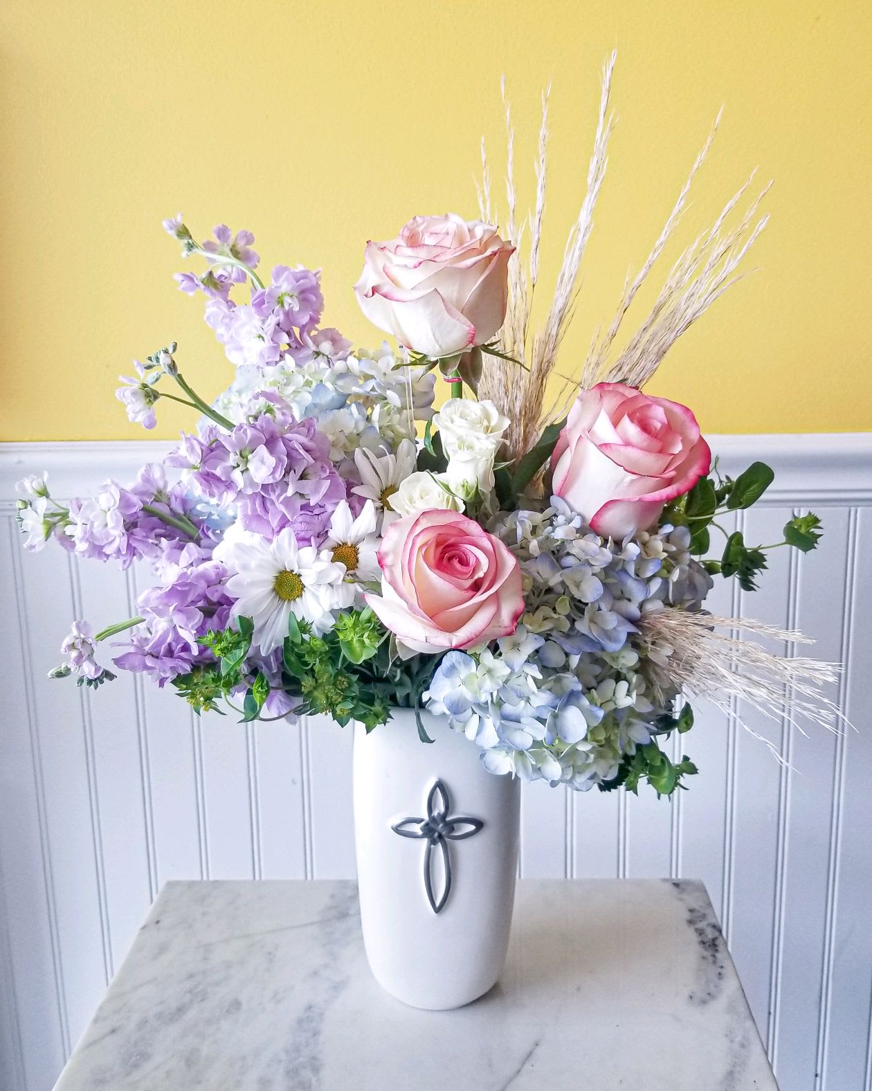 Pink roses and lavender flowers in a white vase