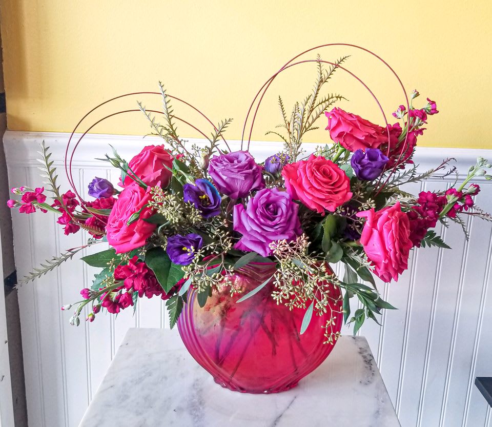 Pink and purple roses arranged in a round glass vase