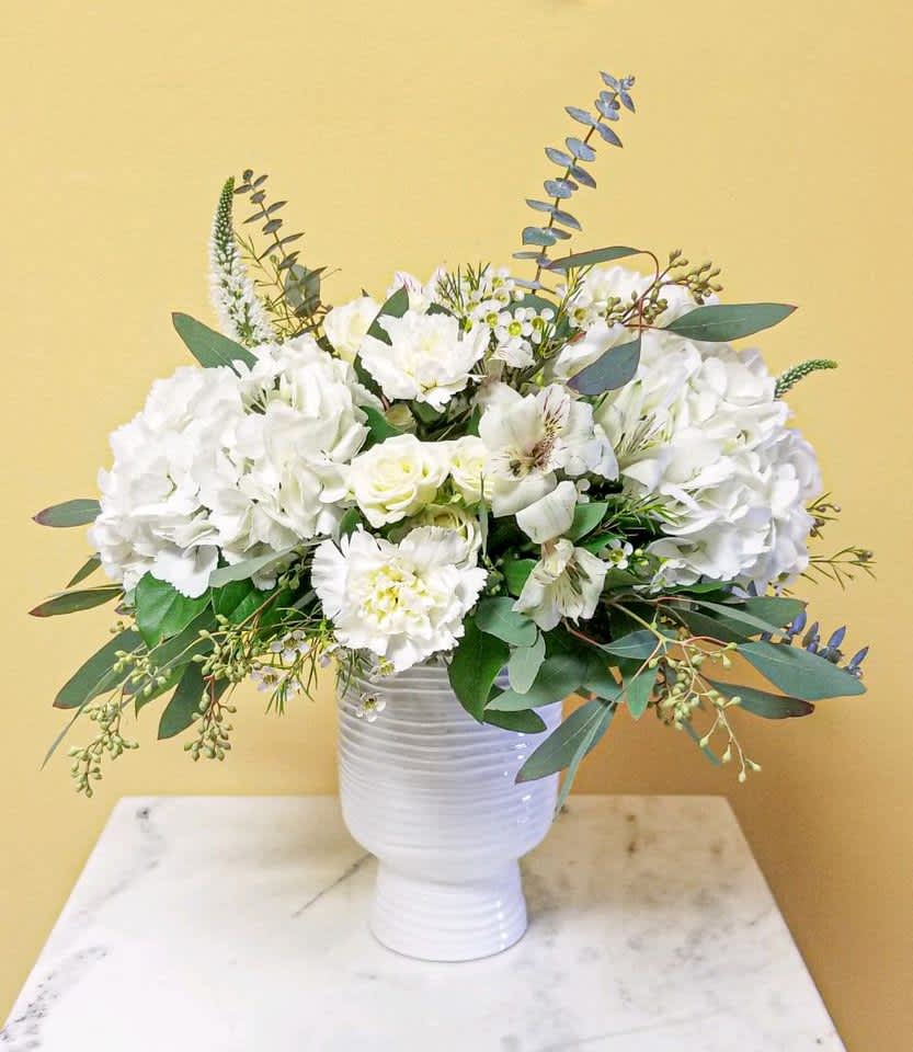 White floral arrangement in a white vase with eucalyptus