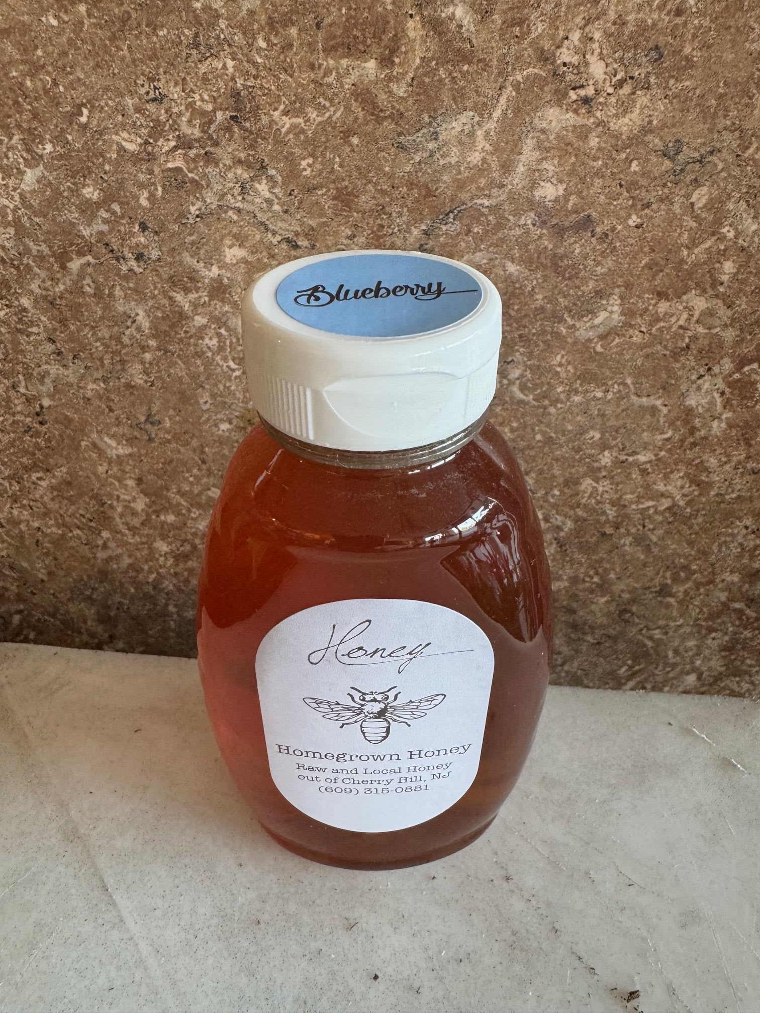 A plastic bottle of blueberry honey with a white cap