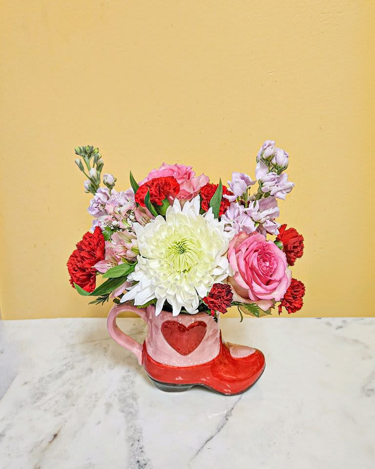 Pink and red flower arrangement in a heart-shaped mug and boot container