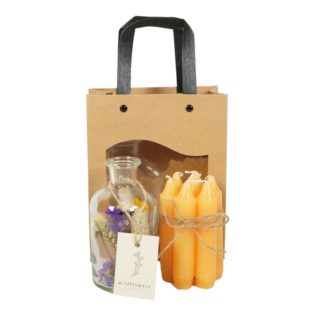 Gift bag with a glass bottle of dried flowers and a bundle of orange candles