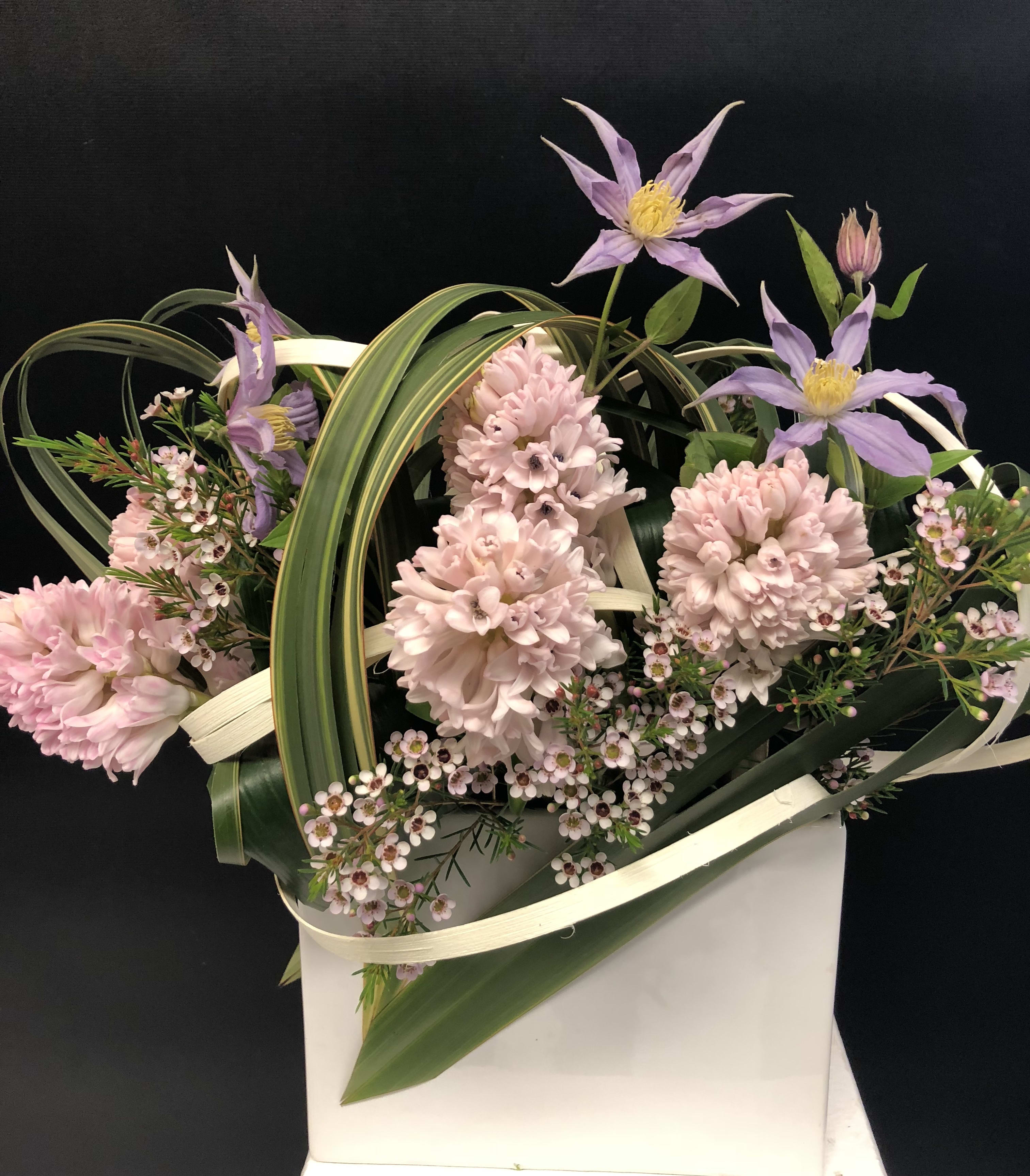 Pink and lavender flowers arranged in a white gift bag