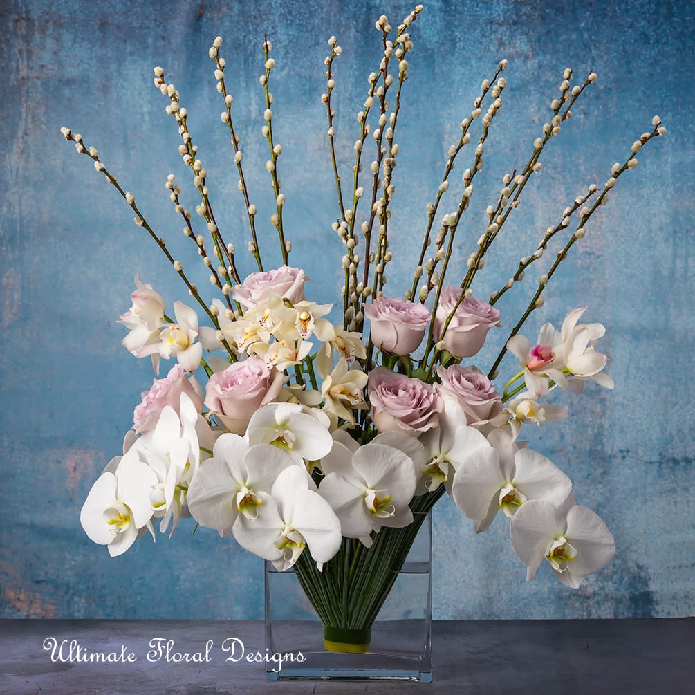 White orchids and pale pink roses in a clear rectangular vase