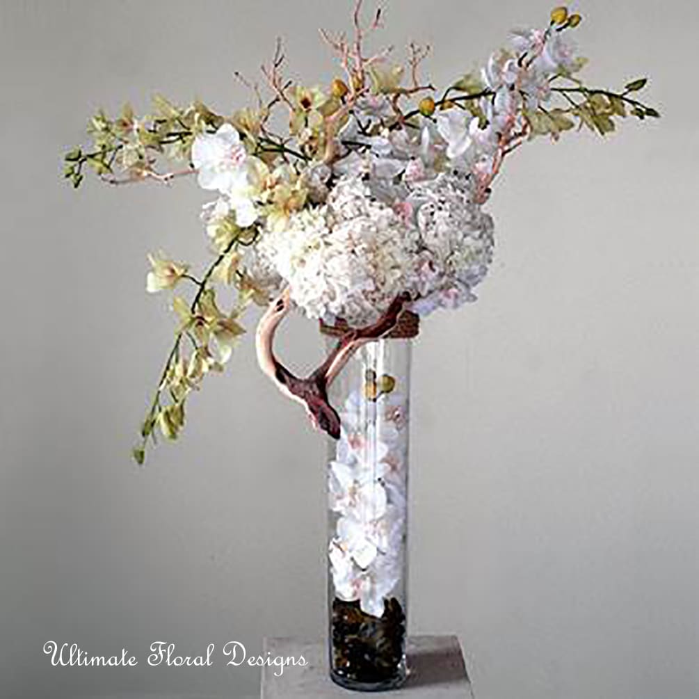 Tall white floral arrangement in a clear glass vase with arching branches