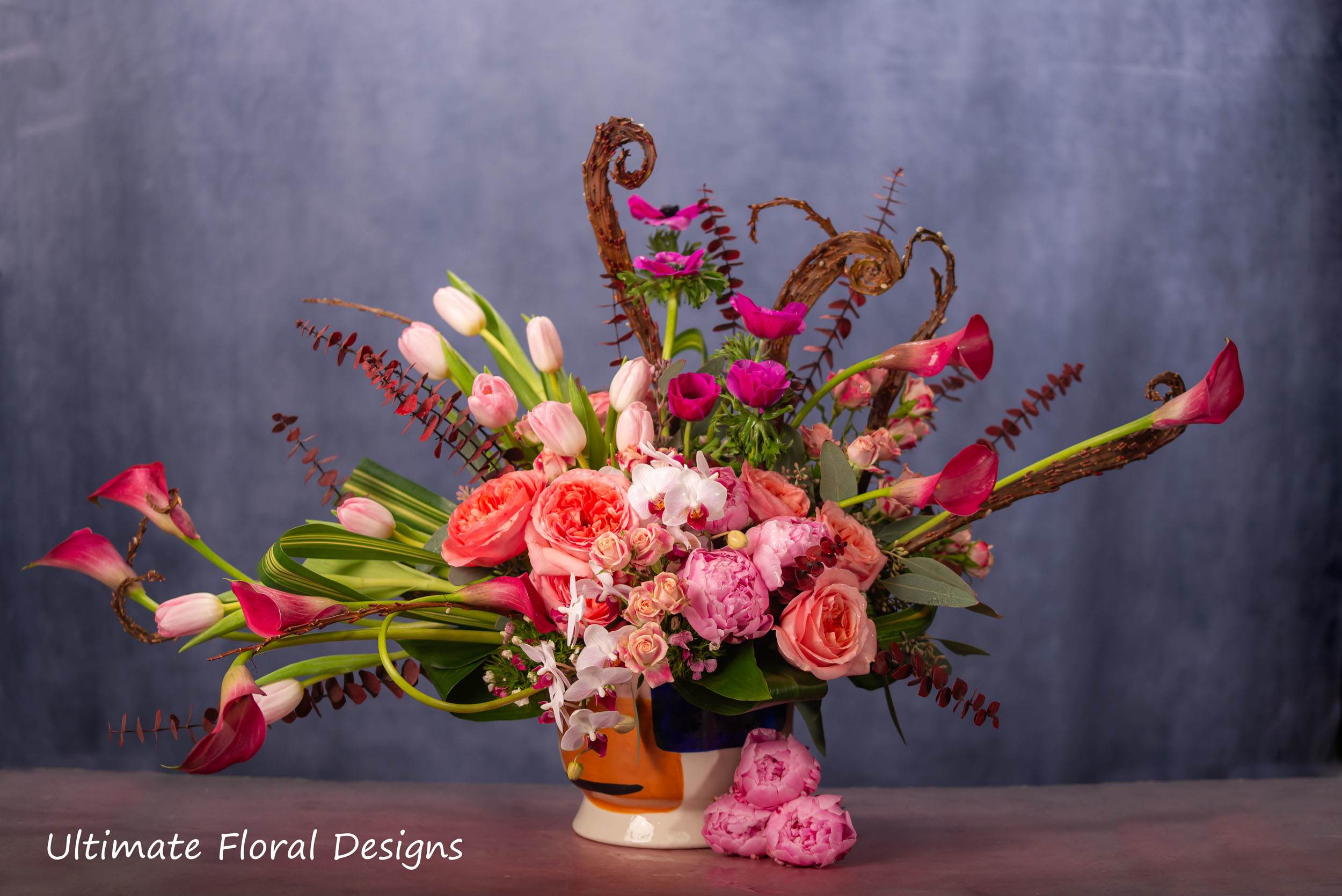 Pink and coral floral arrangement in a decorative ceramic vase