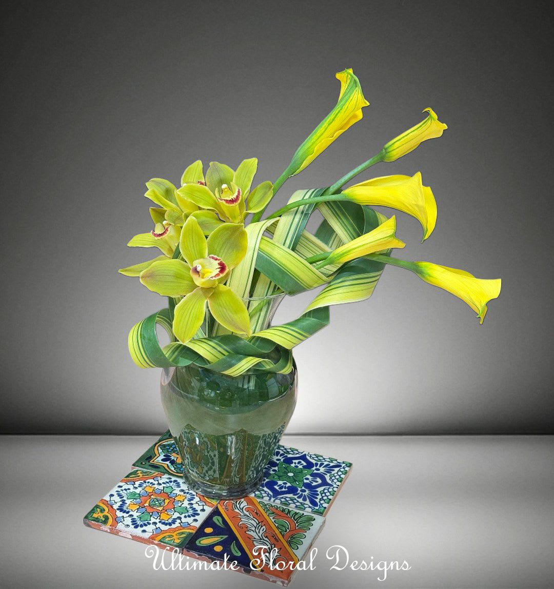 Yellow-green orchids in a glass vase on patterned tiles