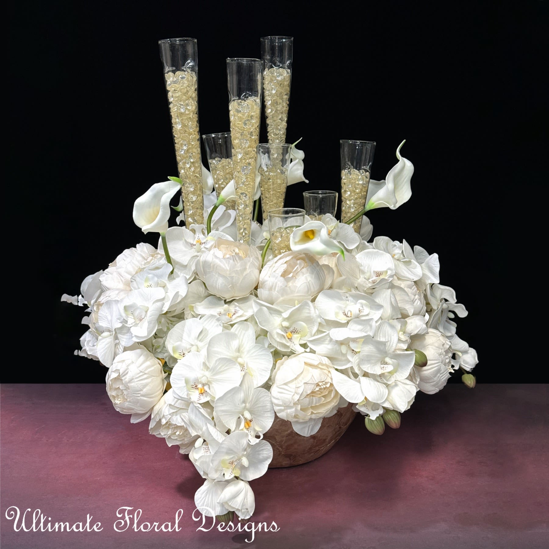 White floral arrangement with orchids, calla lilies, and tall glass cylinders