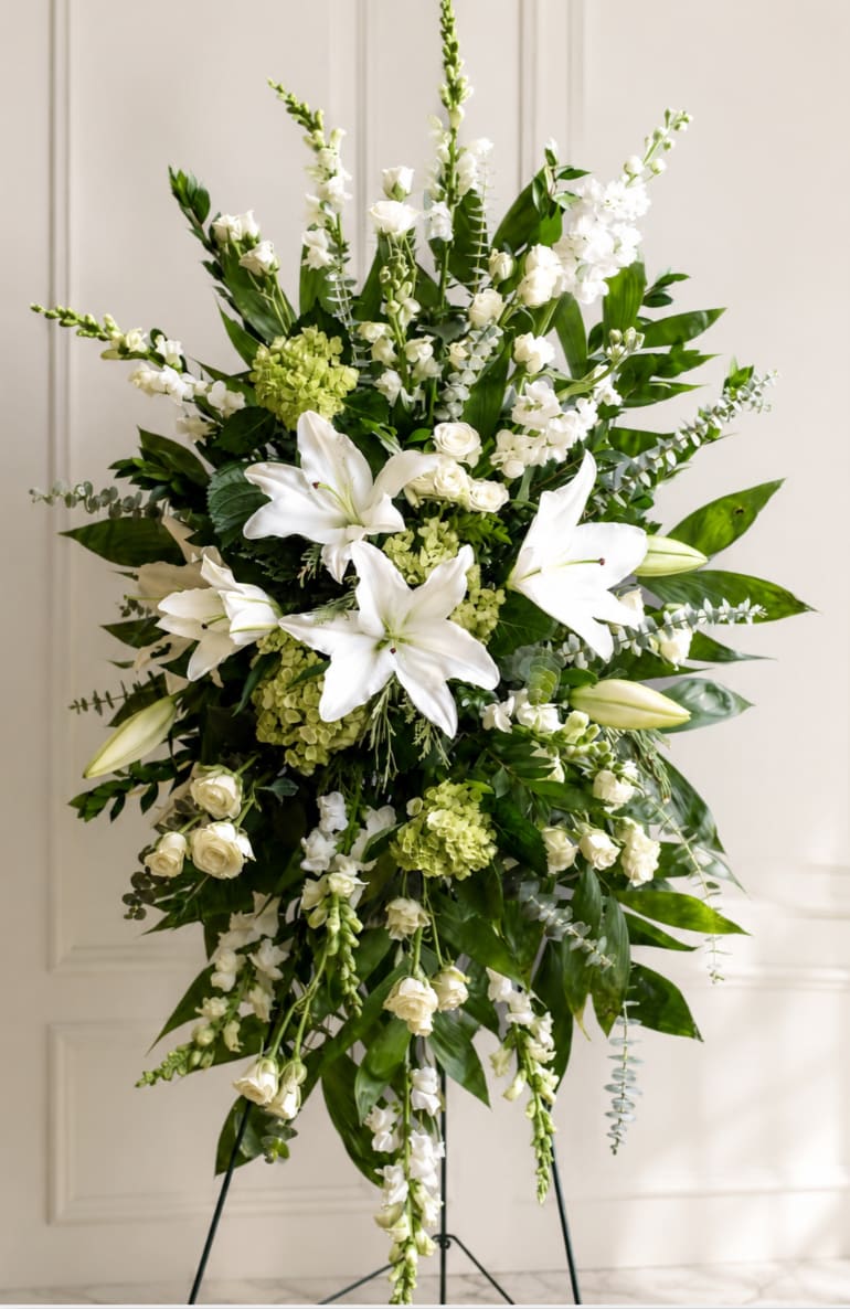 Tall white floral standing spray with lilies and roses on an easel