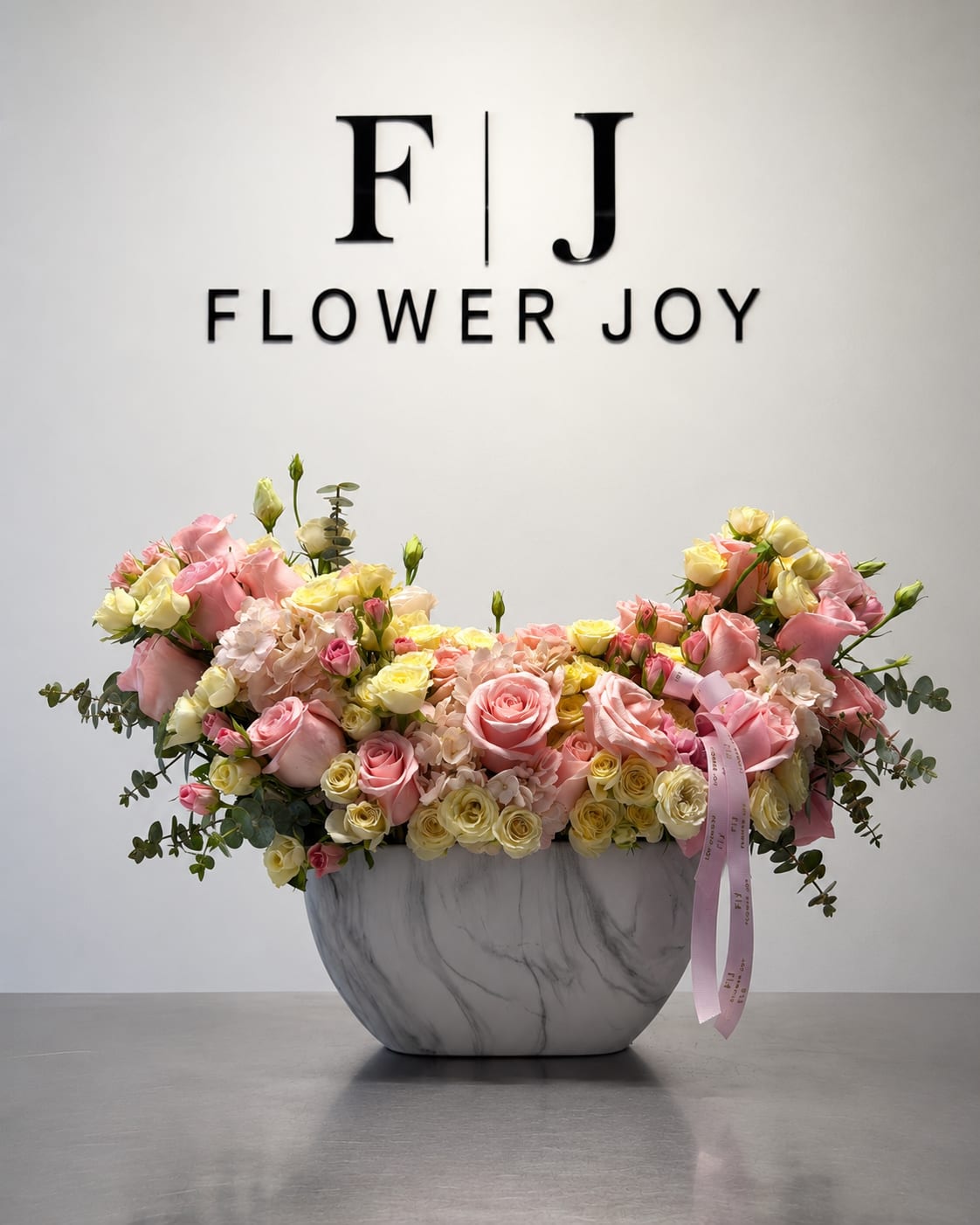 Blush Sunshine Garden - A graceful arrangement of pink and soft yellow roses, delicate hydrangeas, and fresh eucalyptus, beautifully displayed in a modern marble-style vase. Bright, elegant, and full of warmth, perfect for birthdays, congratulations, anniversaries, or joyful celebrations.
