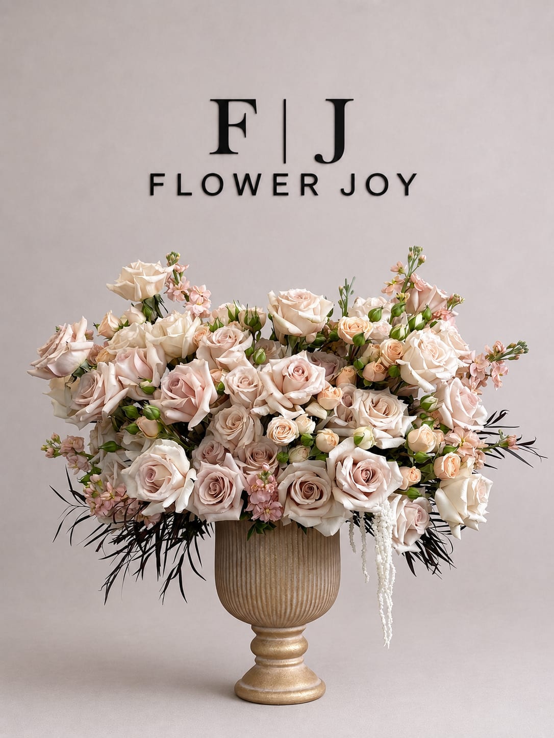 Champagne Garden Arrangement - A luxurious arrangement of champagne and blush roses, delicate spray roses, and soft seasonal accents, beautifully displayed in an elegant pedestal vase. Romantic and sophisticated, perfect for weddings, anniversaries, engagements, or grand celebrations.
