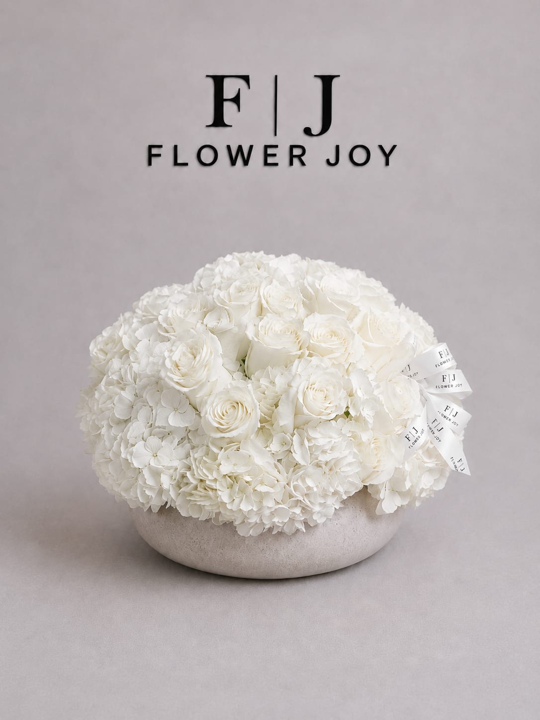 Ivory Harmony Arrangement - A refined arrangement of white roses and lush hydrangeas, beautifully presented in a modern stone-textured vase. Soft, elegant, and timeless—perfect for weddings, sympathy gestures, anniversaries, or sophisticated celebrations.