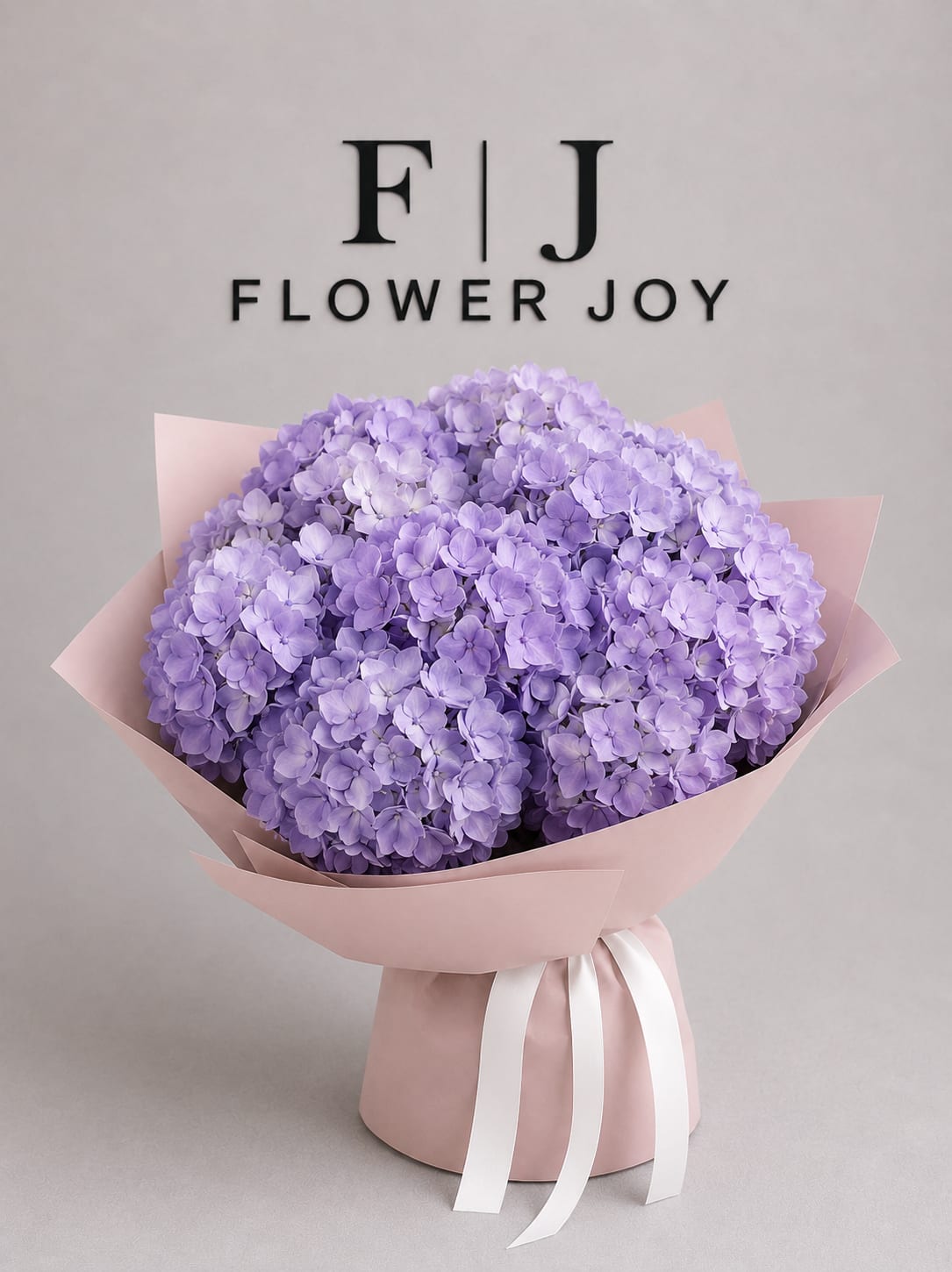 Lavender Hydrangea Grace - A soft and dreamy bouquet of lavender hydrangeas wrapped in blush pink paper with elegant white ribbons. Perfect for birthdays, congratulations, and thoughtful everyday gifts.