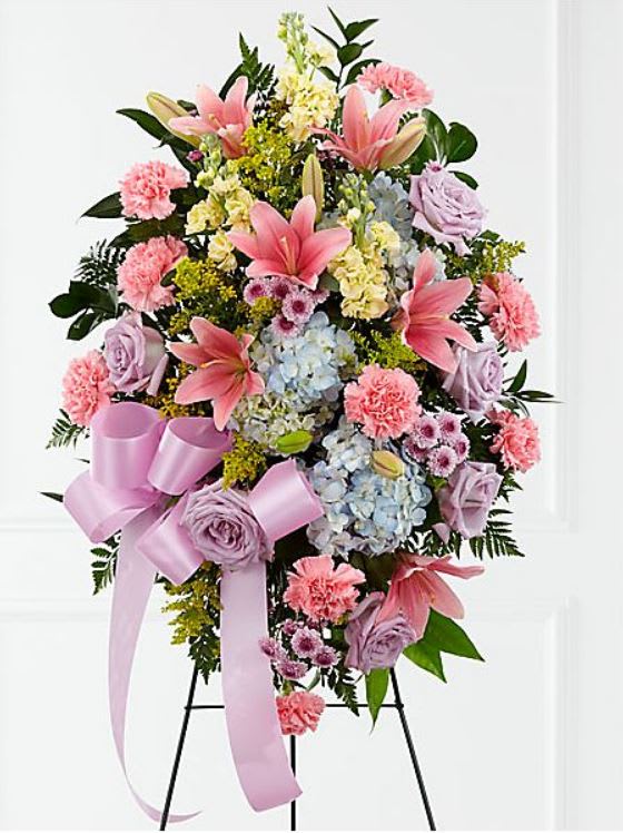Standing floral spray with pink lilies, roses, hydrangeas, and a lavender ribbon
