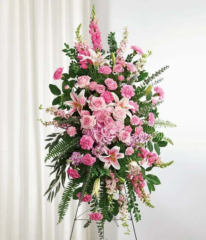 Pink Standing Spray - A stunning standing spray designed with an array of pink flowers, including roses, lilies, and carnations, complemented by lush green ferns and foliage. 