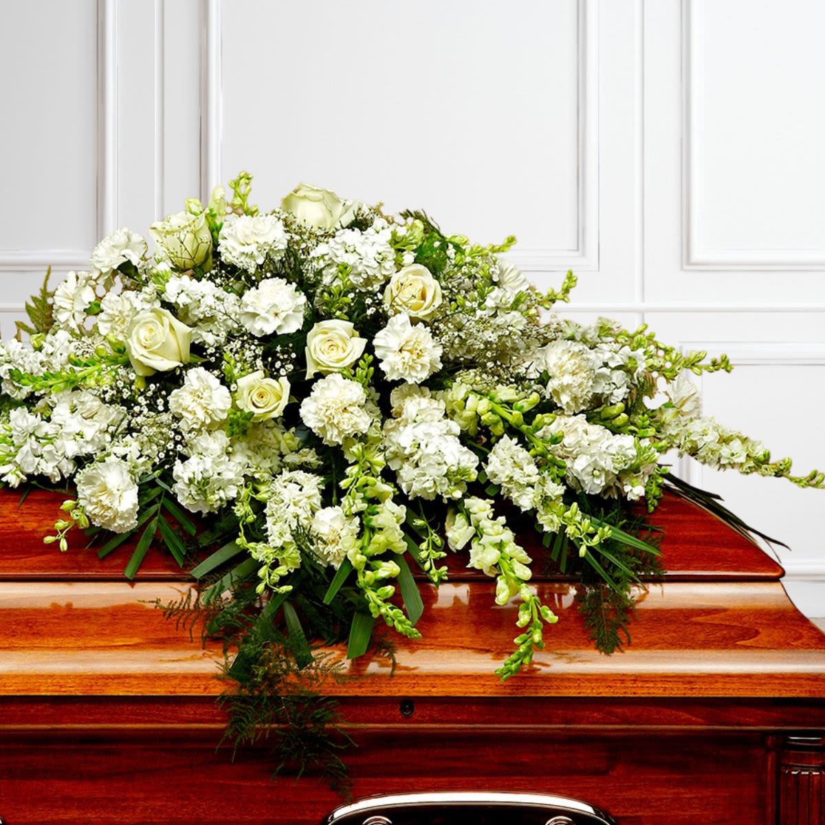 All White Half-Size Casket Cover - Elegant, timeless, and deeply meaningful, our All White Casket Spray is a beautiful tribute to honor a loved one's life and memory. Designed with fresh white flowers such as roses, carnations, snapdragons, and other seasonal blooms, this graceful arrangement rests atop the casket as a symbol of love, peace, and remembrance.