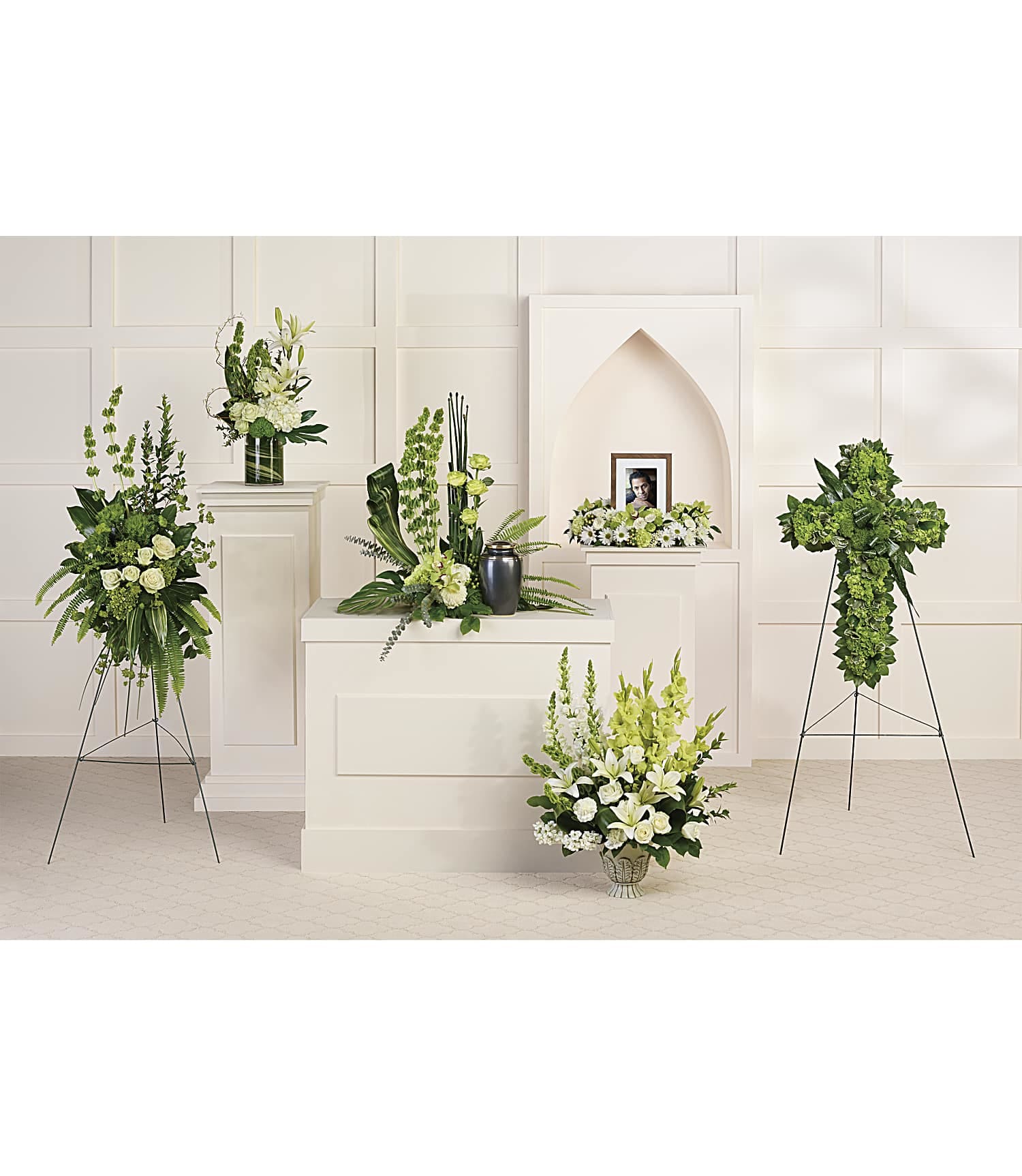 White and green funeral floral arrangements around a framed photo