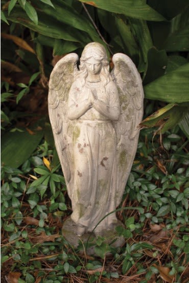 Stone angel statue standing among garden plants